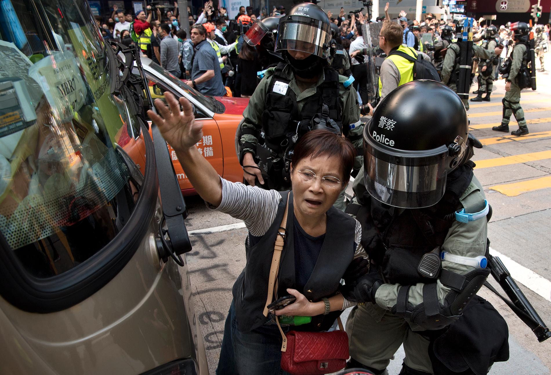 En demonstrerande kvinna förs undan av polis.