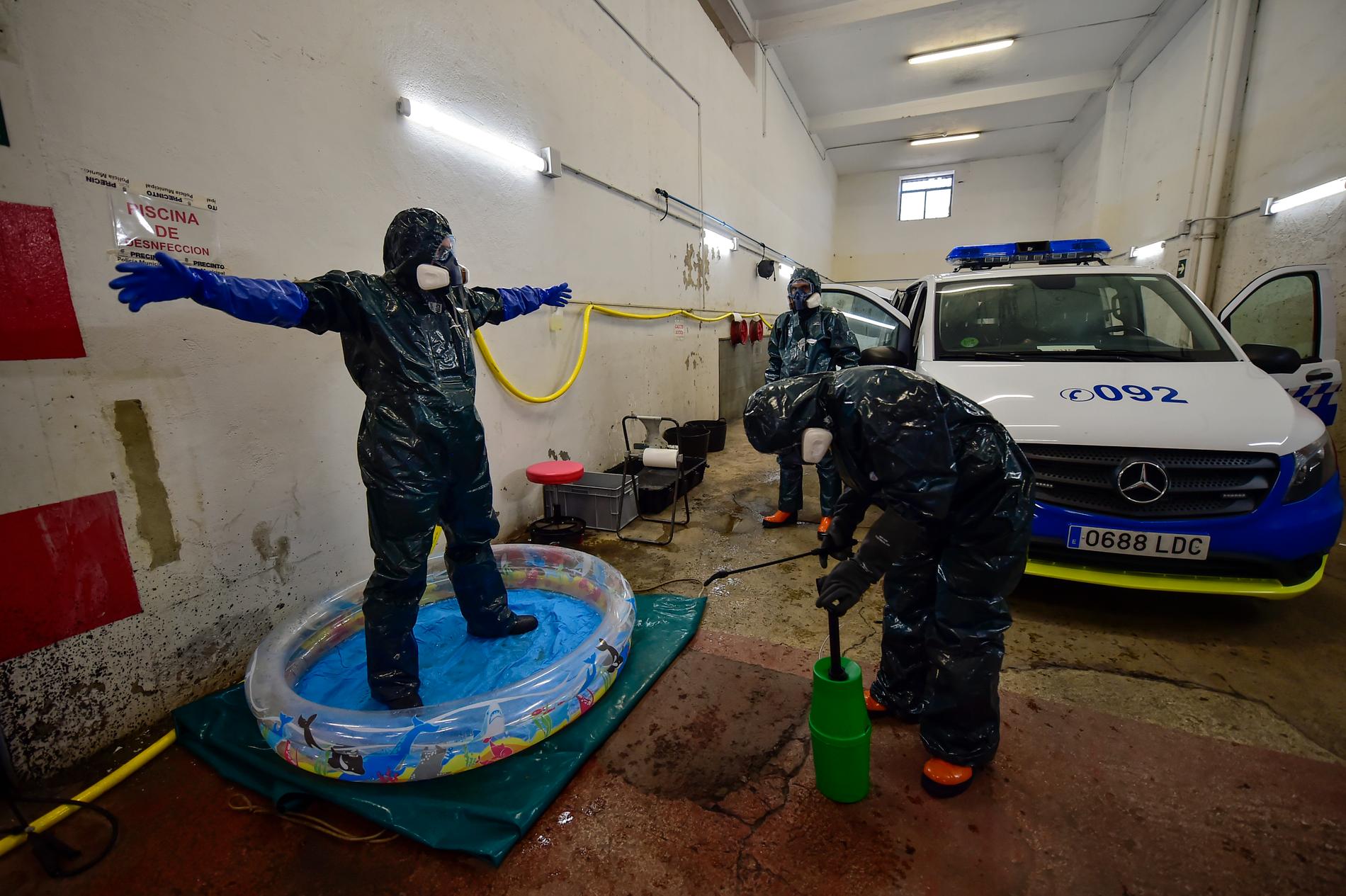 En volontärarbetare med specialutrustning disinfekteras på en polisstation i Pamplona. 