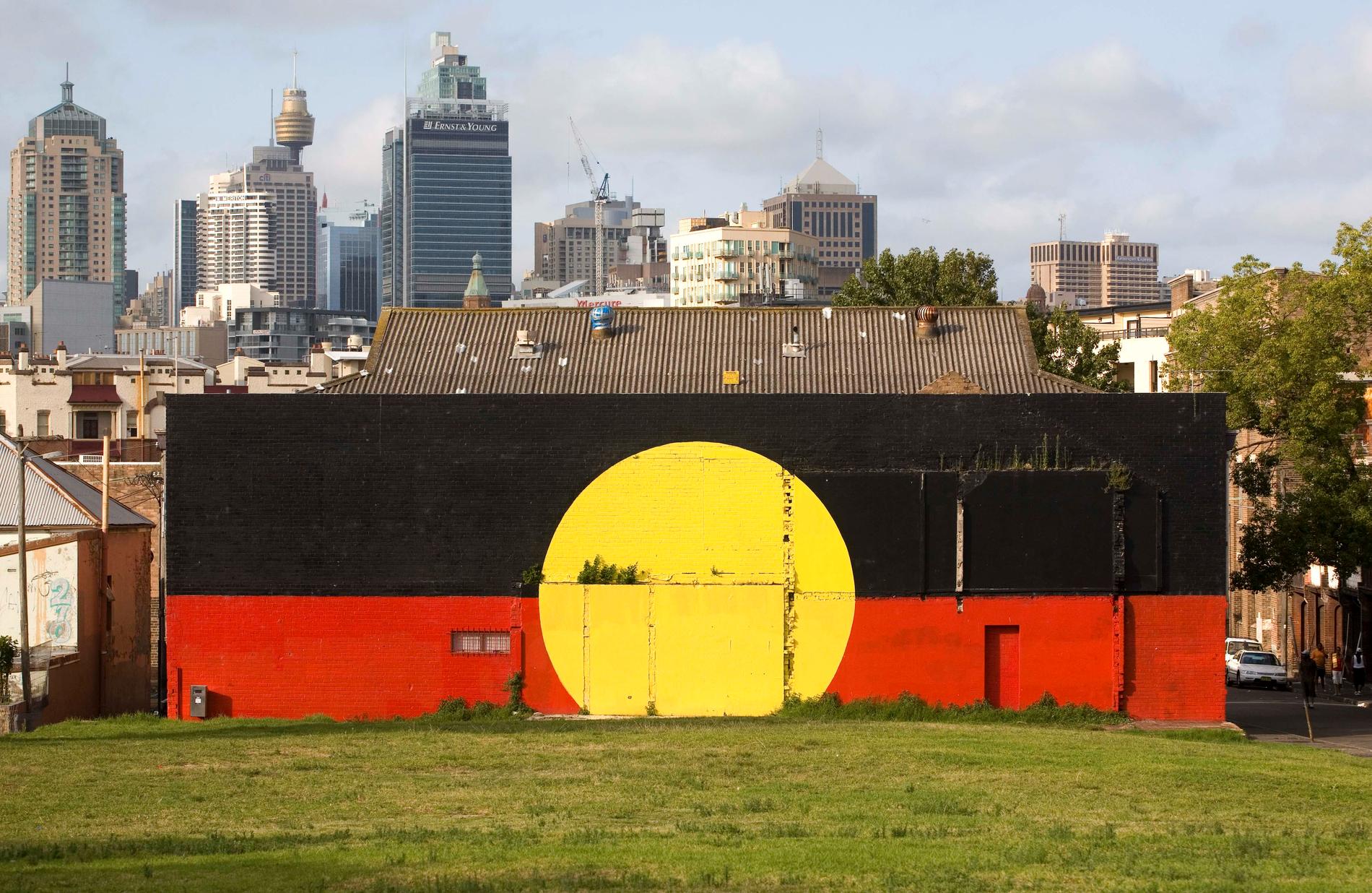 Australiens ursprungsbefolkning aboriginernas flagga målad på en vägg i Sydney. Arkivbild.
