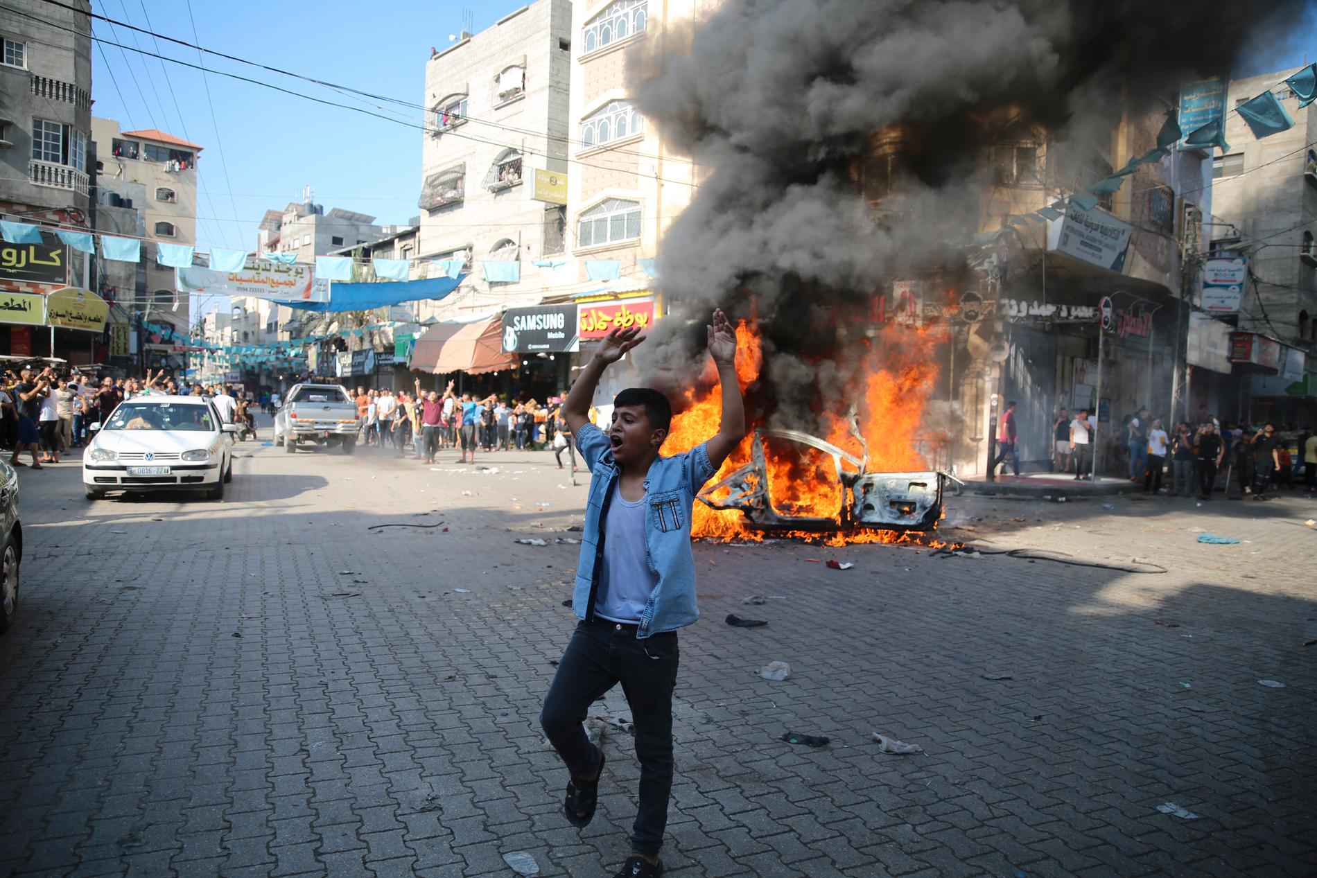 Palestinier firar efter att ha satt en israelisk bil i brand.