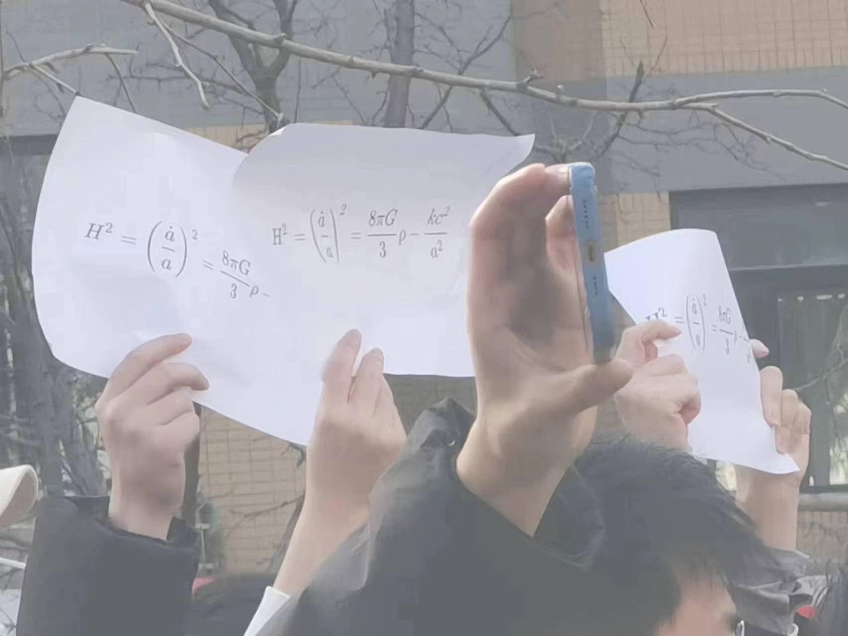 Studenter vid Tsinghua-universitet i Beijing håller upp A4-papper med Friedmanns ekvation. Friedmann uttalas som ”free man” i Kina.