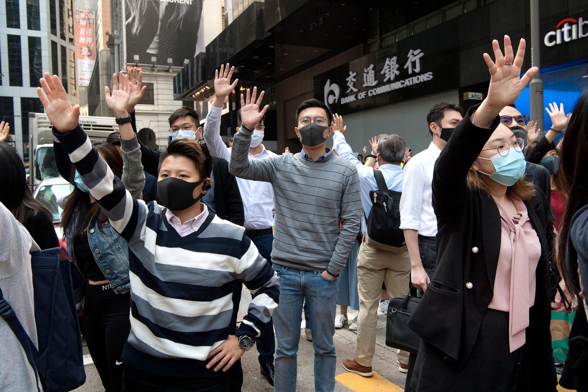 Anställda i Hongkongs finanskvarter demonstrerar på sin lunchrast i protest mot polisens brutalitet, men också för att visa att de stödjer demokratirörelsens krav på den lokala regeringen. Bilden är tagen i november 2019.