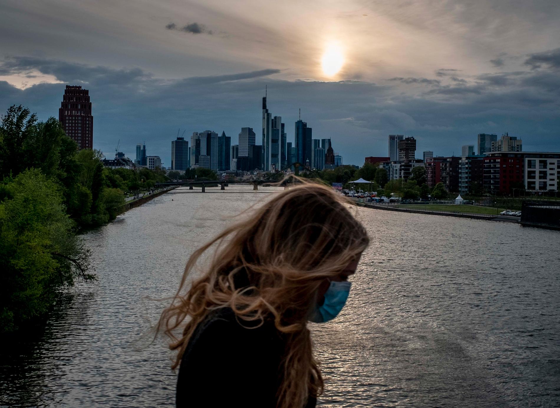 En kvinna med munskydd på en bro över floden Main i Frankfurt. Bilden är från i torsdags.