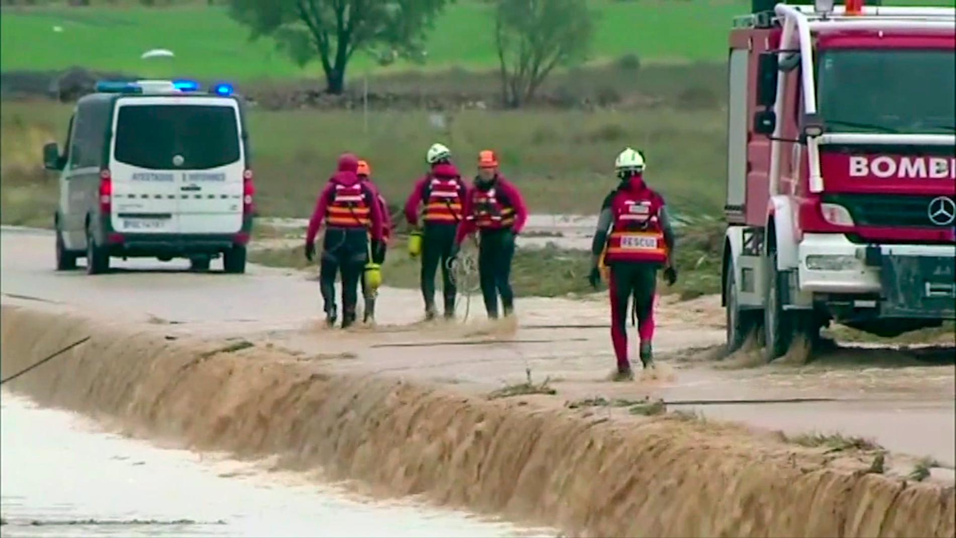 Personal från räddningstjänsten nära platsen där två personer omkom i en vattenfylld bil sydost om staden Valencia.