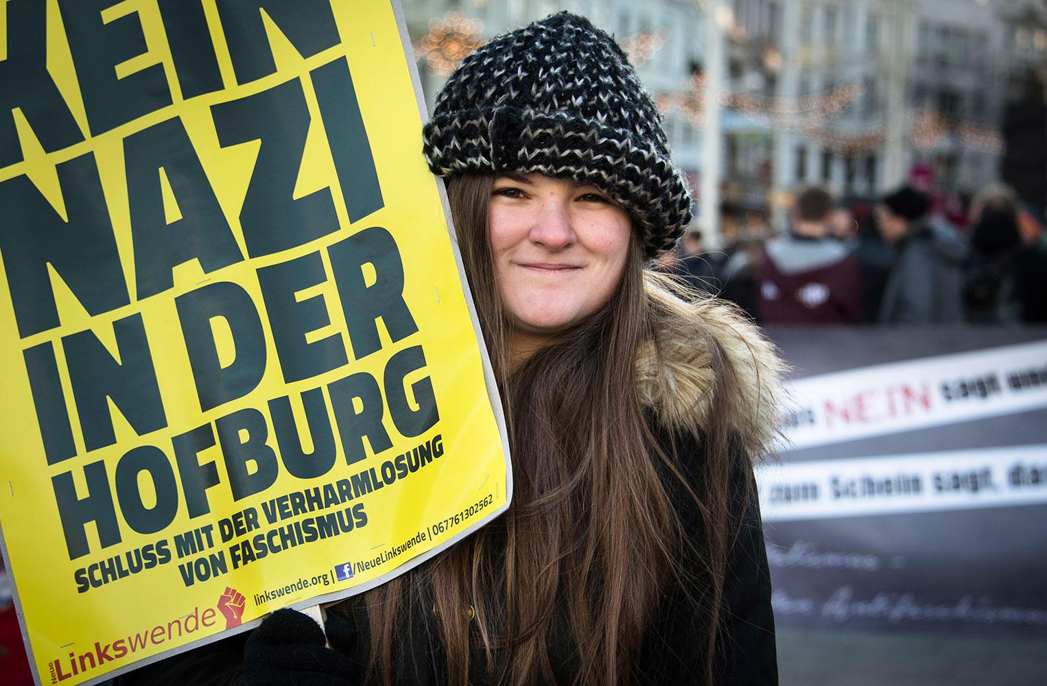 Ung kvinna håller upp ett plakat under demonstrationen mot Norbert Hofer.