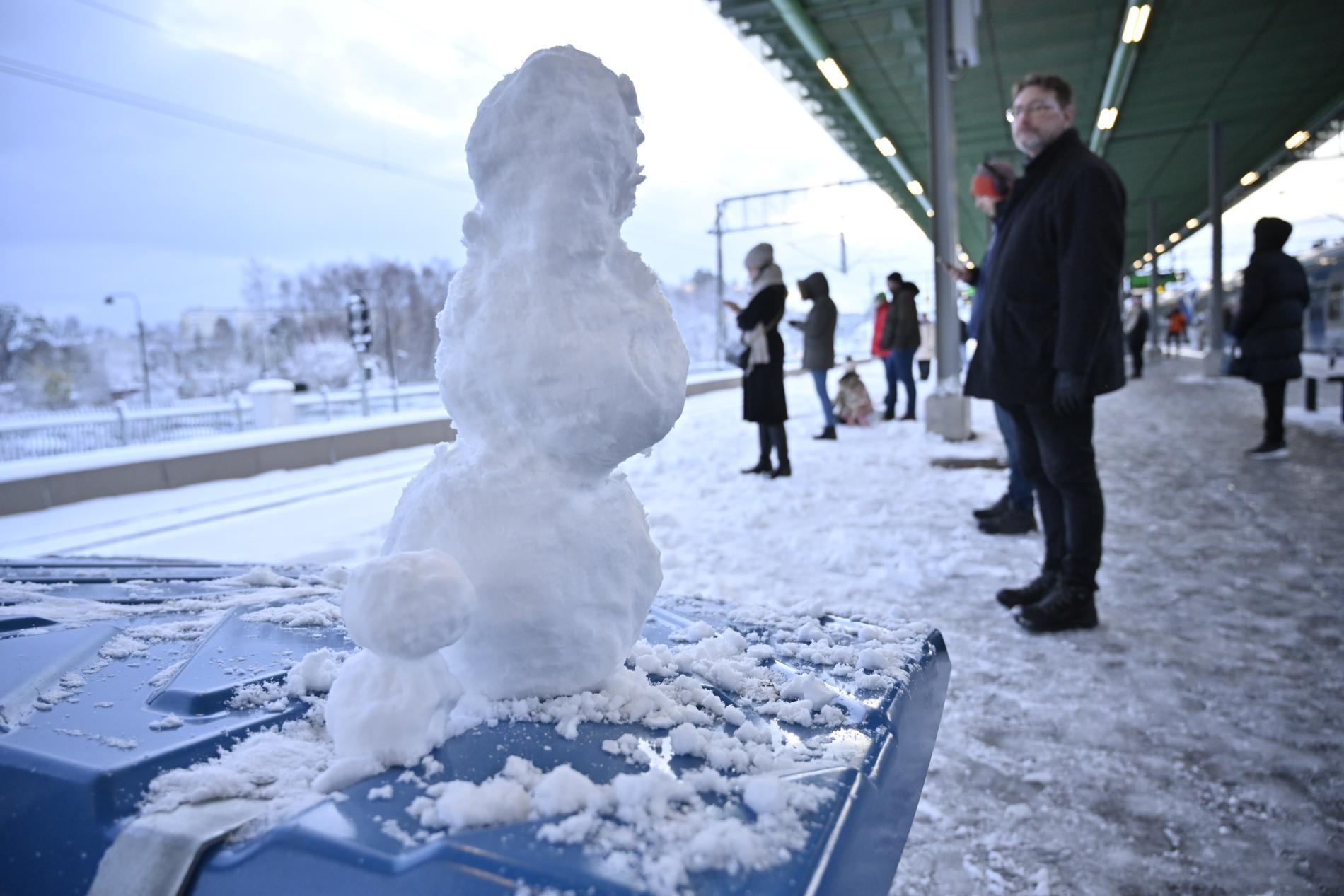 Snögubbar och resenärer på Kallhälls pendeltågsstation i Stockholm.