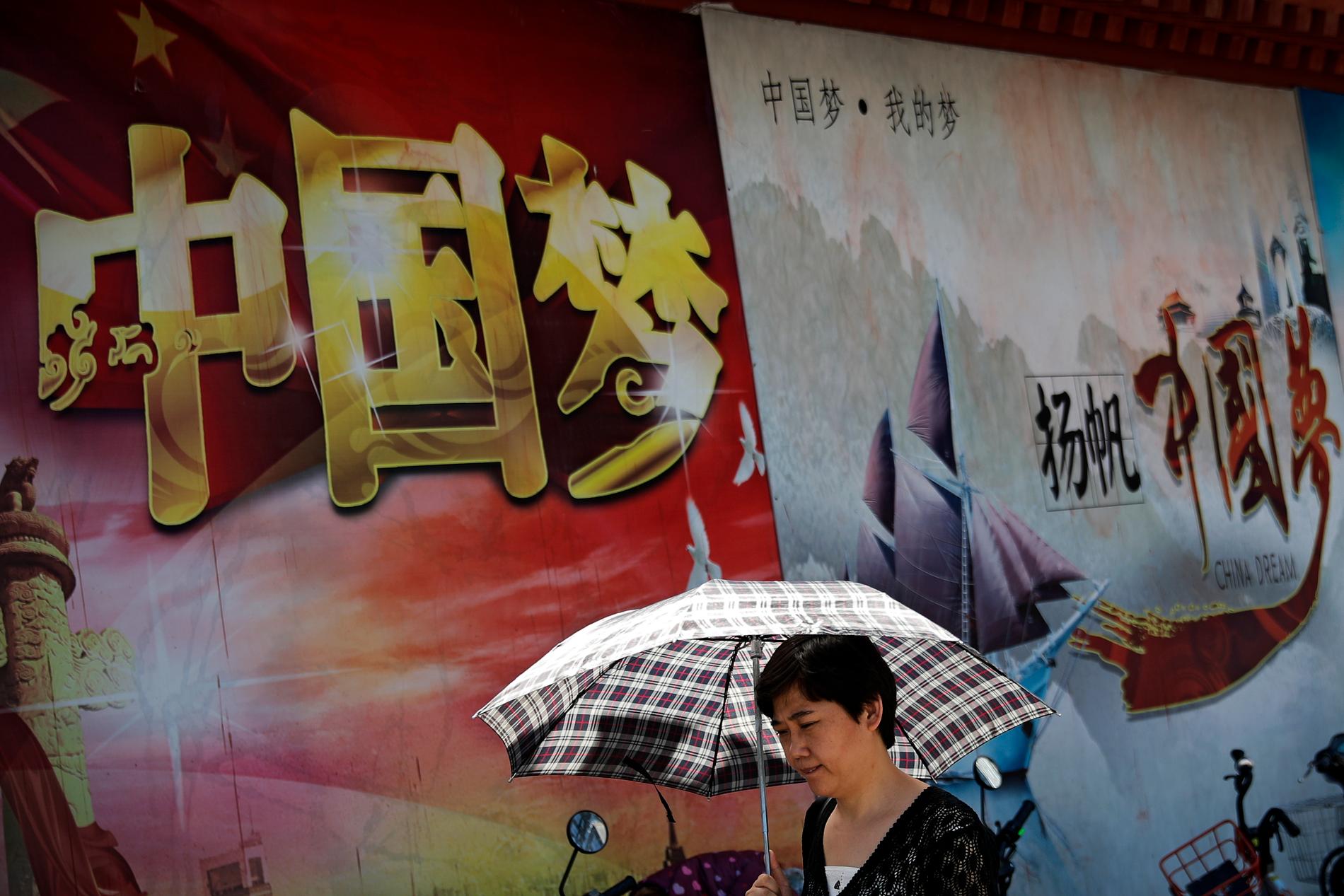 En kvinna går förbi ett propagandaplakat från Kommunistpartiet i Peking. Partiets centralkommitté möts i veckan för att diskutera modernisering och förbättring av det kinesiska styret.