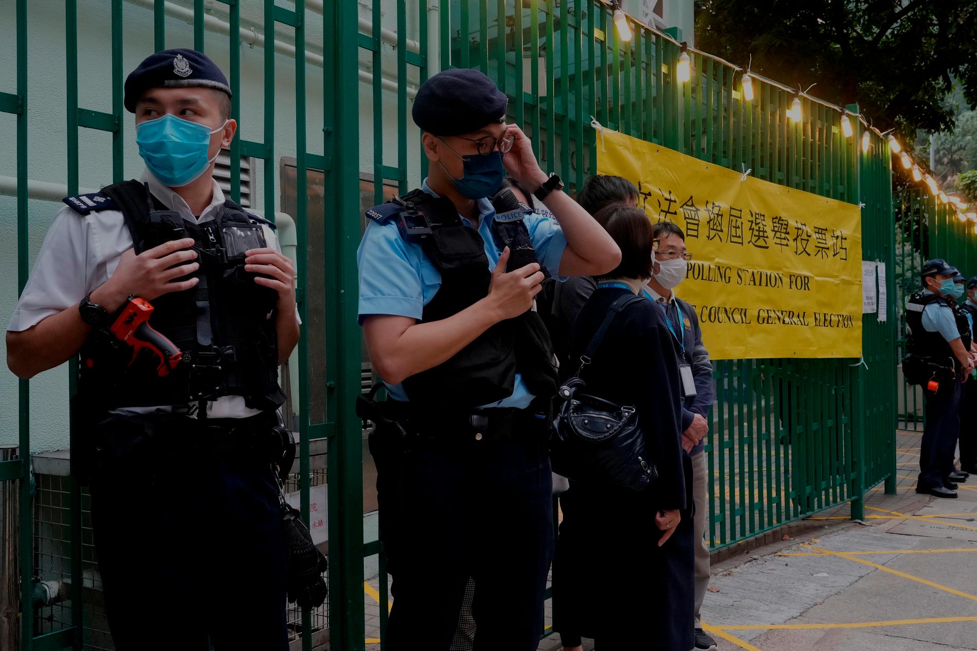 Poliser på vakt utanför en vallokal i Hongkong den 19 december. Det var det första valet som hölls efter att Peking lagstiftade om att alla valbara kandidater skulle vara lojala med kommunistpartiet. Arkivbild.