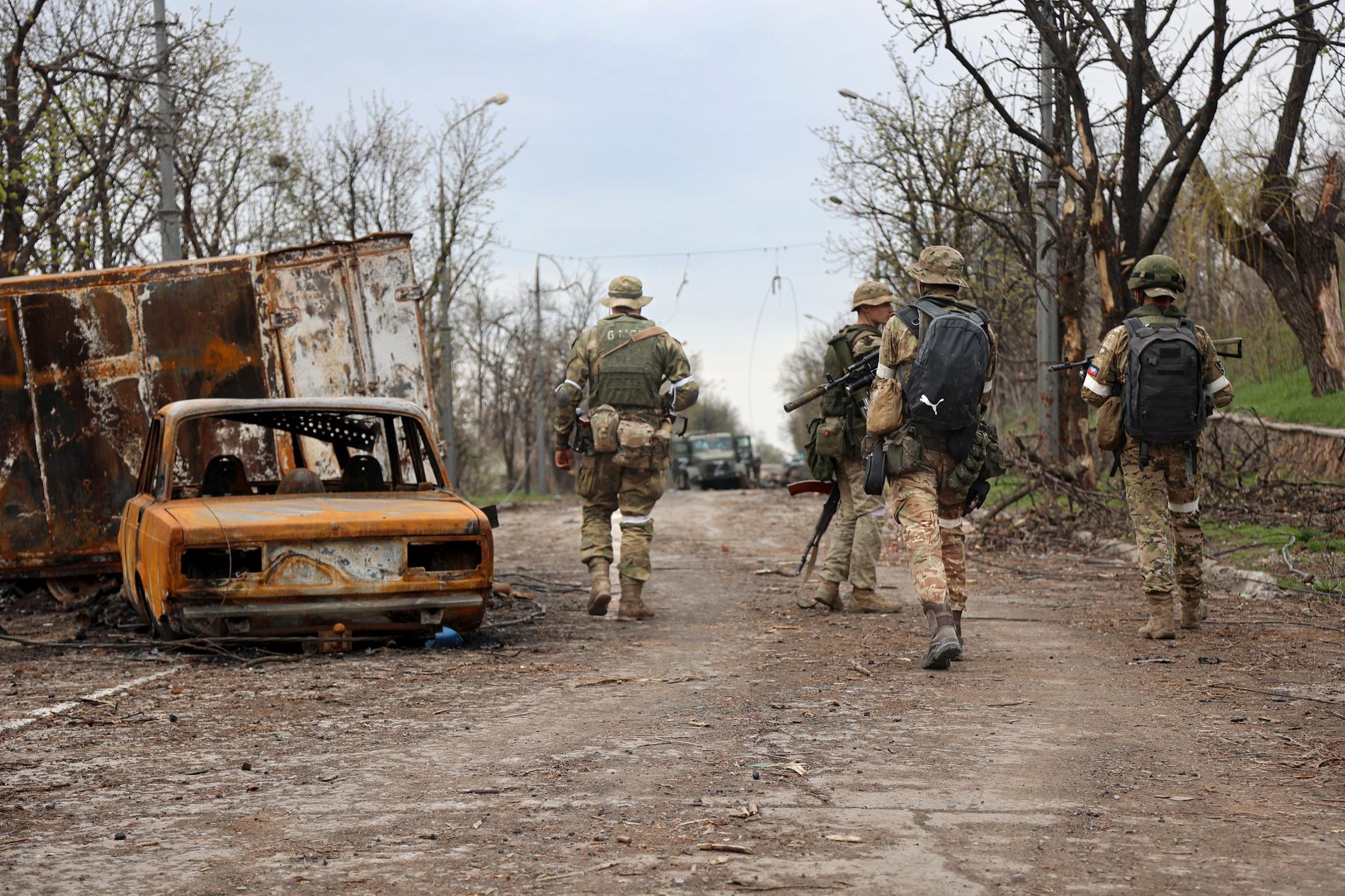 Milissoldater i Donetsk passerar ett bilvrak förstört under de hårda striderna i ett området. Regionen kontrolleras av ryskstödda separatiststyrkor.
