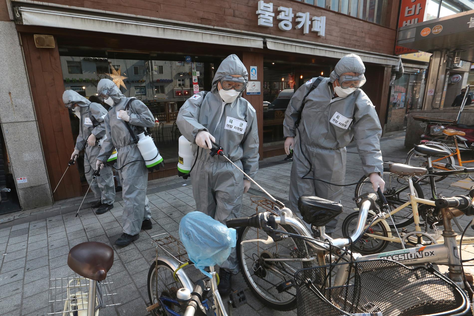 Sydkoreanska soldater i skyddsutrustning desinficerar en gata i Seoul. Arkivbild.