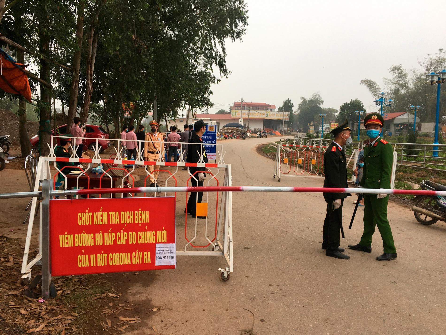 Poliser på vakt vid en vägspärr vid Son Loi utanför Vietnams huvudstad Hanoi under torsdagen. Området är försatt i karantän sedan sex fall av coronaviruset covid-19 upptäckts där.