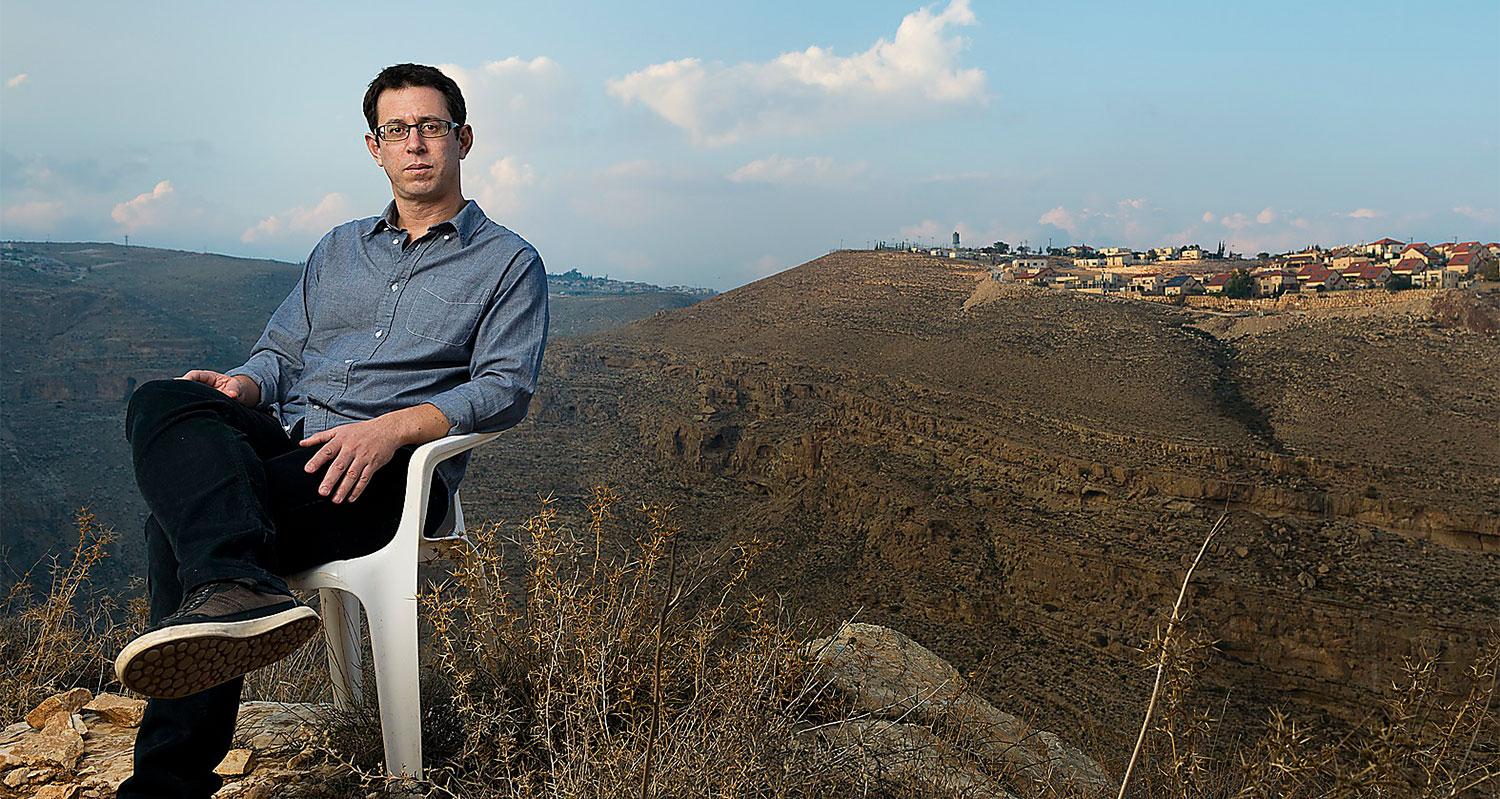 Israeliske författaren Assaf Gavron (född 1968) med en av bosättningarna på Västbanken i bakgrunden. Foto: Jonathan Bloom