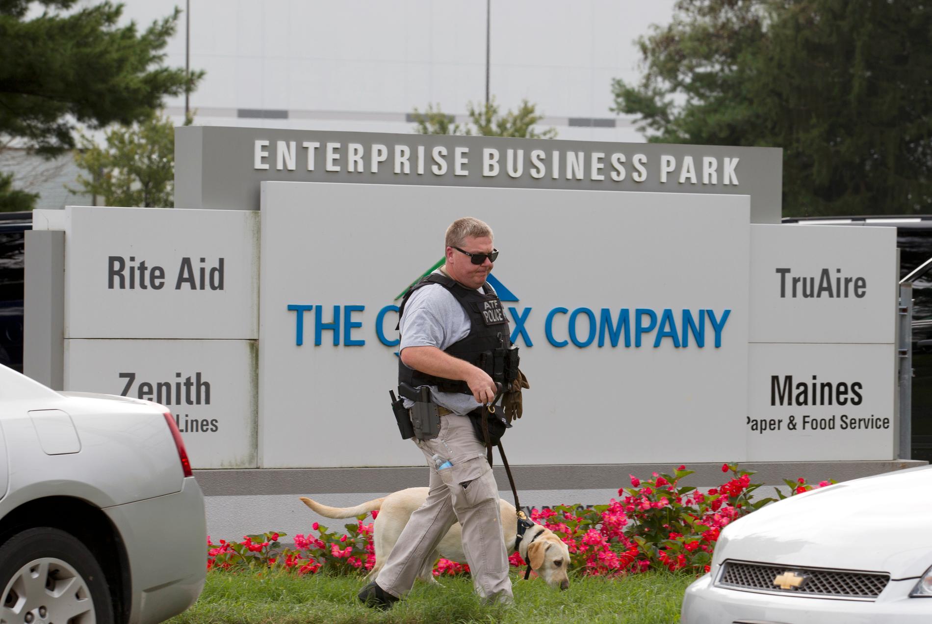 En polis med sökhund utanför företagsparken där tre personer sköts ihjäl i Maryland, USA.
