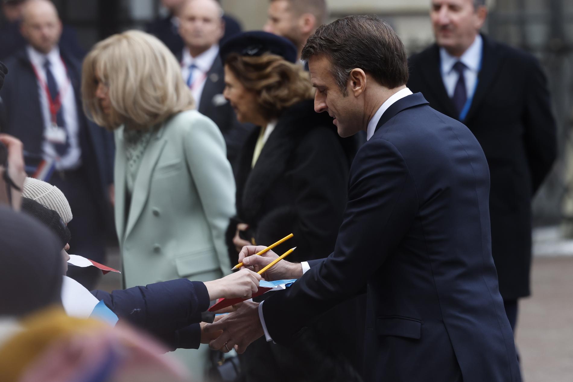 Macron skriver autografer på borggården. 