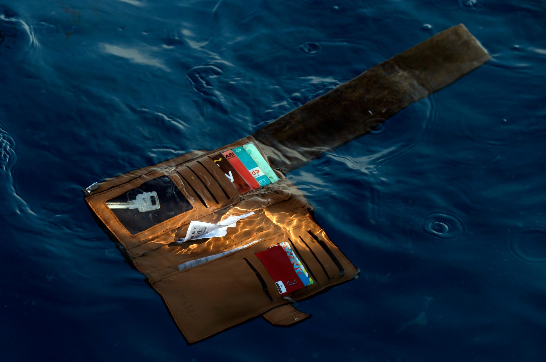 En plånbok tillhörande en av passagerarna på det störtade flygplanet flyter i vattnet i närheten av platsen där planet störtade.