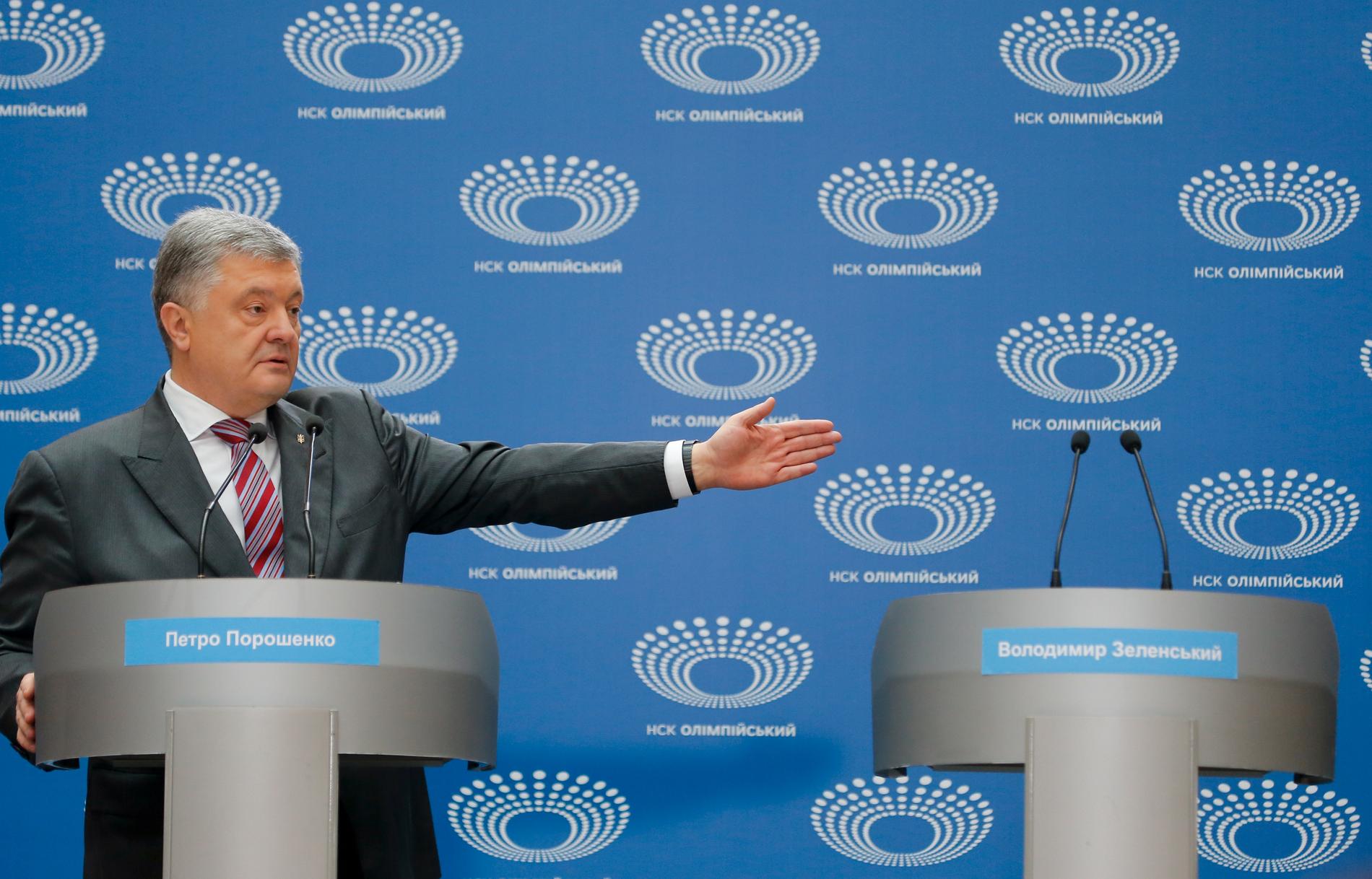 Ukrainas sittande president Petro Porosjenko gestikulerar mot det tomma podiet intill honom. En debatt mellan presidentkandidaterna hade utlysts på fotbollsarenan i Kiev i söndags, men utmanaren Volodymyr Zelenskyj, som inte bekräftat dagen, dök aldrig upp.