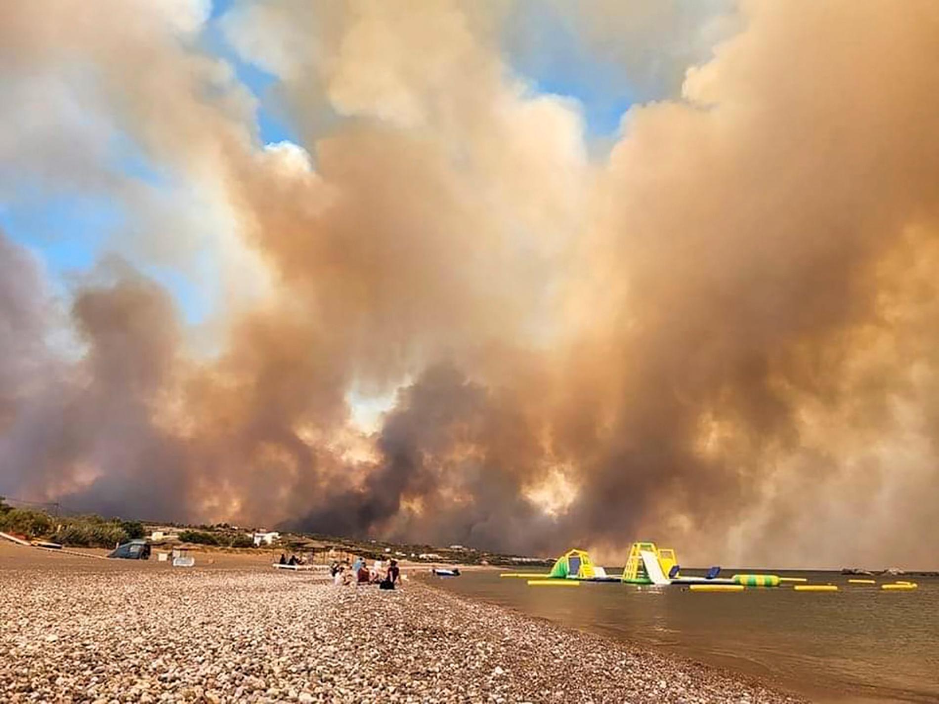 Rökmoln stiger över en strand på Rhodos under lördagen.