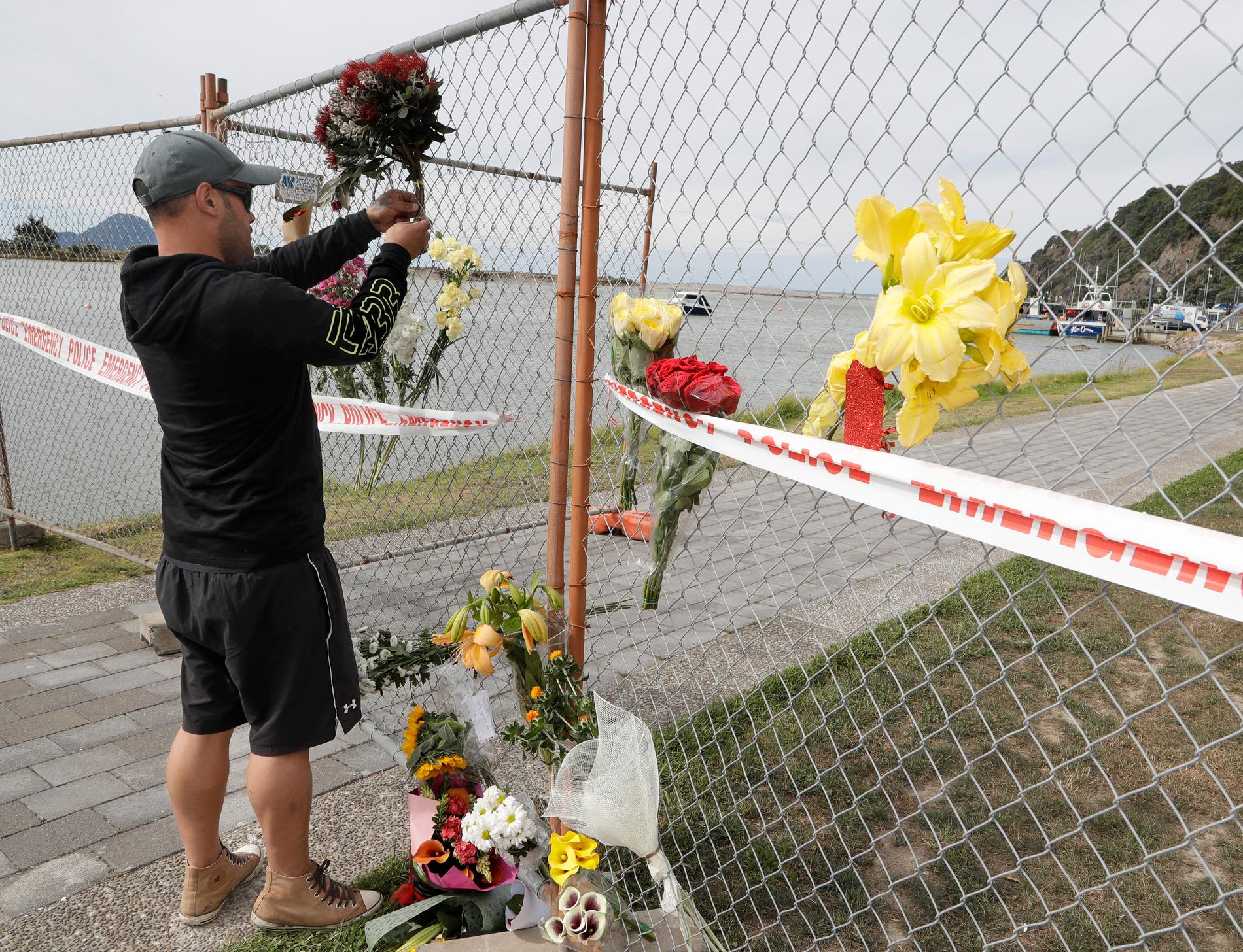 En man lämnar blommor till minne av de omkomna efter vulkanutbrottet på White Island.