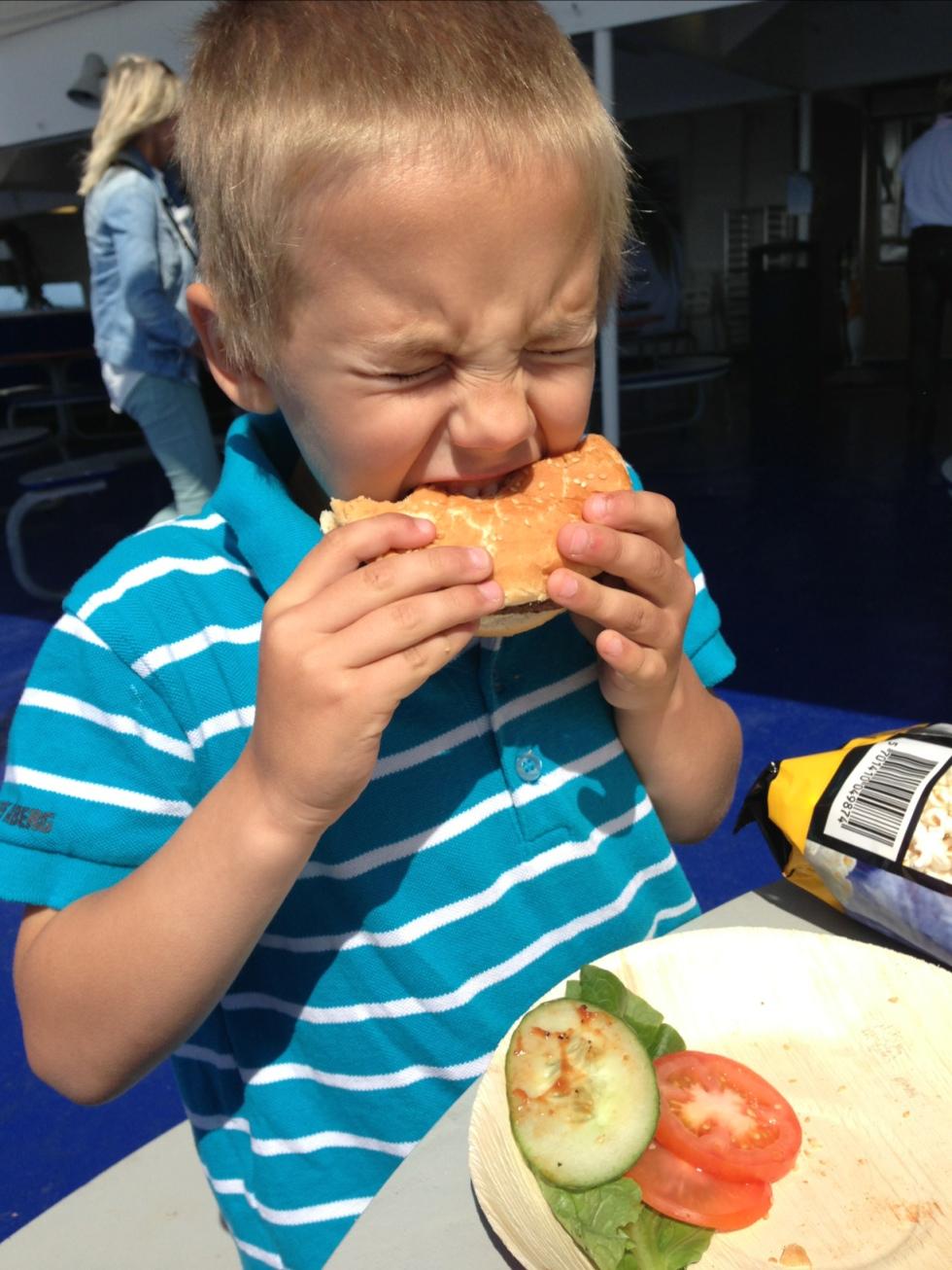 Alexander äter hamburgare ute på däck på färjan mellan Fredrikshamn och Göteborg