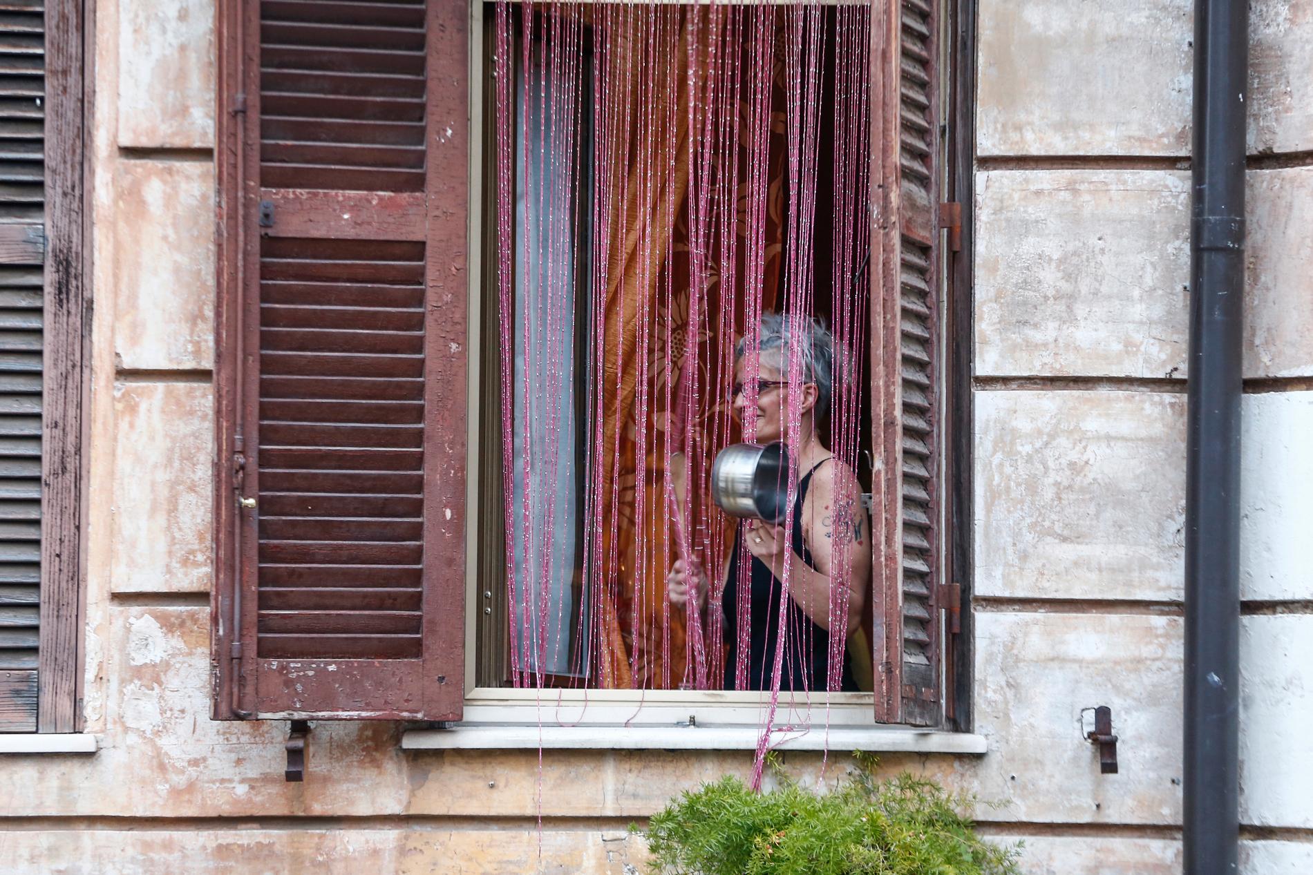 En kvinna i viruskarantän spelar kastrull från sitt fönster i Garbatella i Italiens huvudstad Rom.