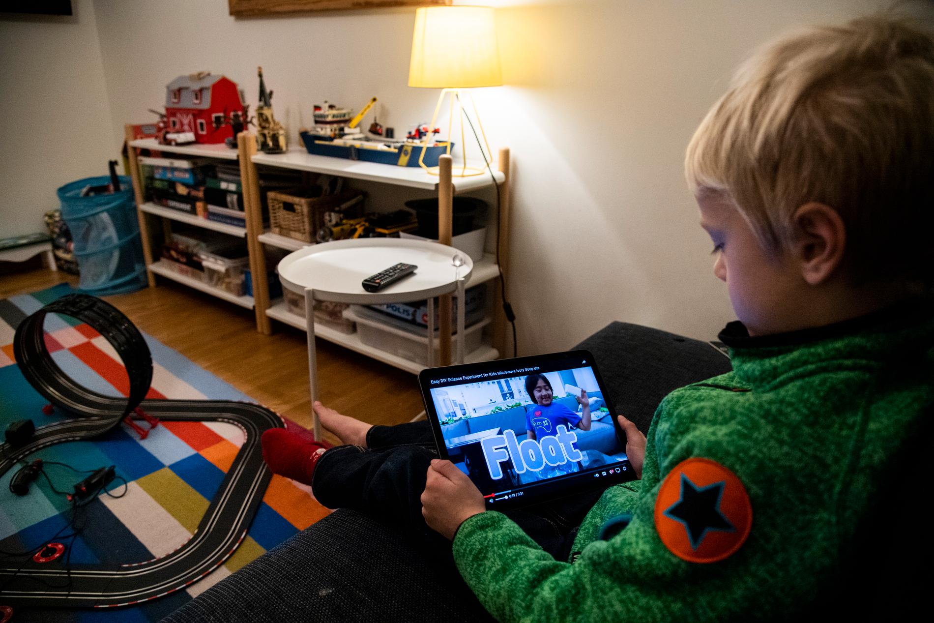 Ett barn sitter och tittar på superinfluencern Ryan Kajis video på en ipad. 