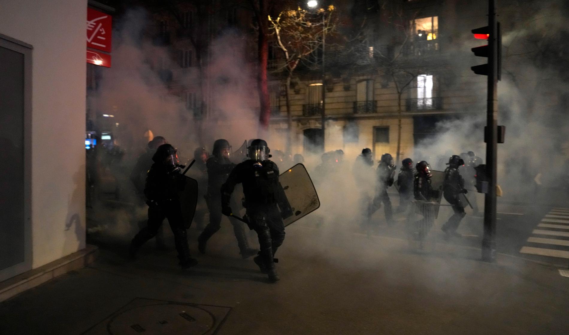 Kravallpolis på väg mot demonstranter i Paris. 
