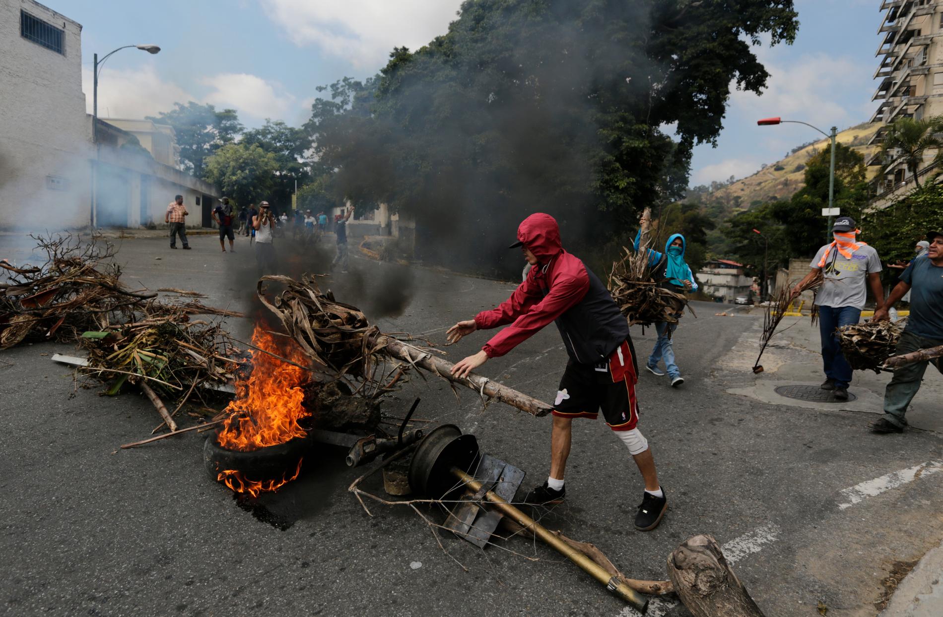 Oppositionsanhängare bygger en brinnande barrikad under sammandrabbningar med säkerhetsstyrkor vid en protest i Caracas-stadsdelen Cotiza till stöd för den grupp militärer som genomförde en kortlivad revolt på måndagen.