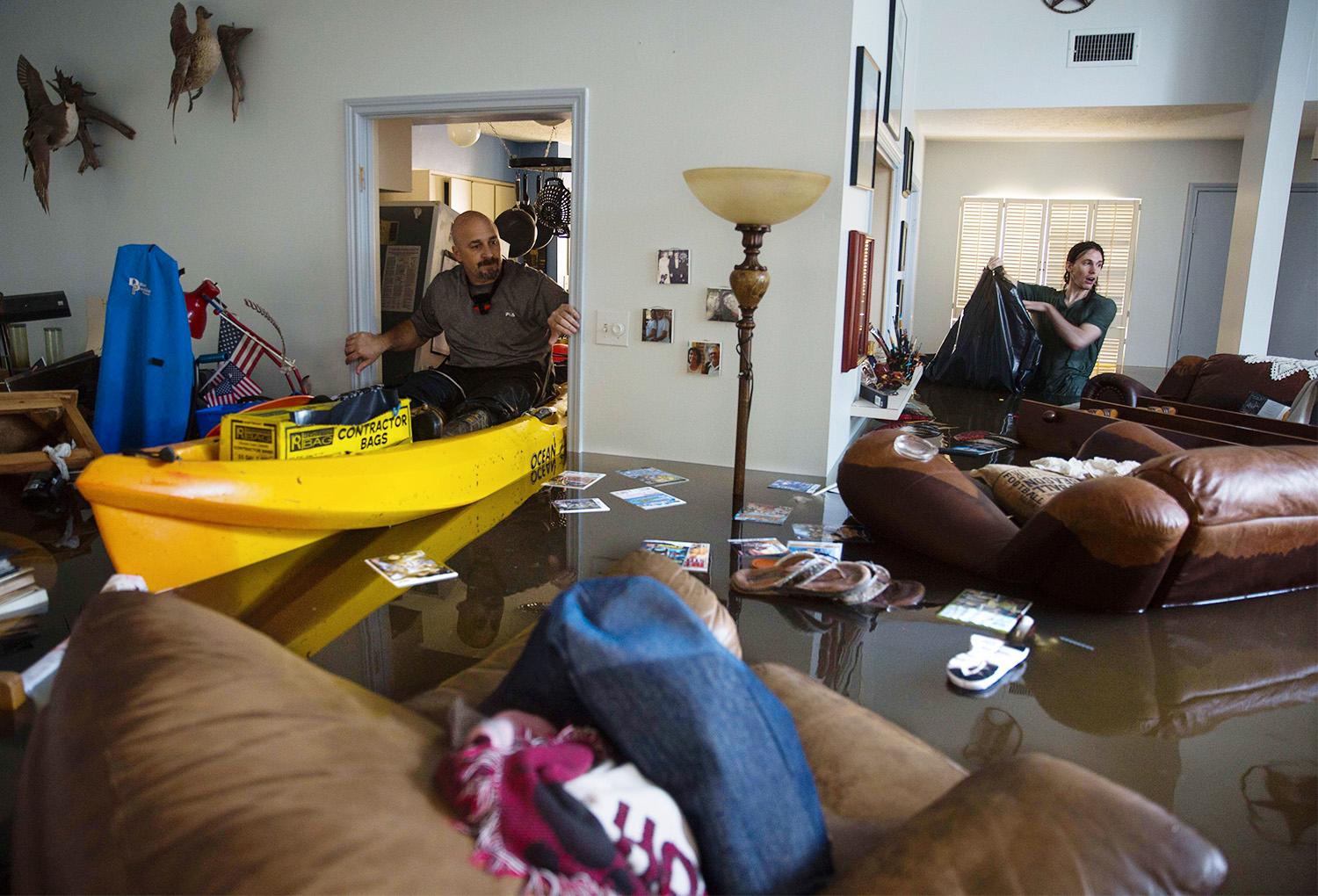 Larry Coser Jr och hans son Matthew försöker rädda värdesaker från Larrys fars hus efter att det svämmats över av vatten i Houston.