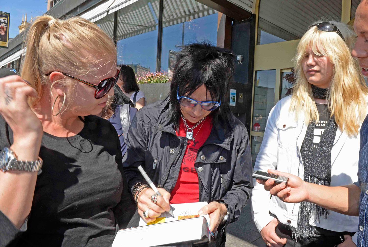 Bandets gitarrist Tommy Henriksen skriver autografer utanför Grand Hotel.