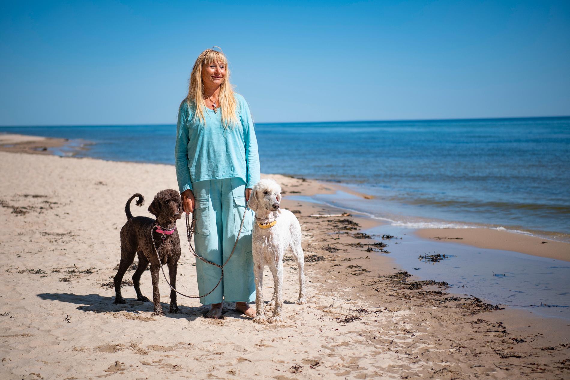 Lena Sandelius, 69, rastar hundarna Stella och Socker på sandstranden.