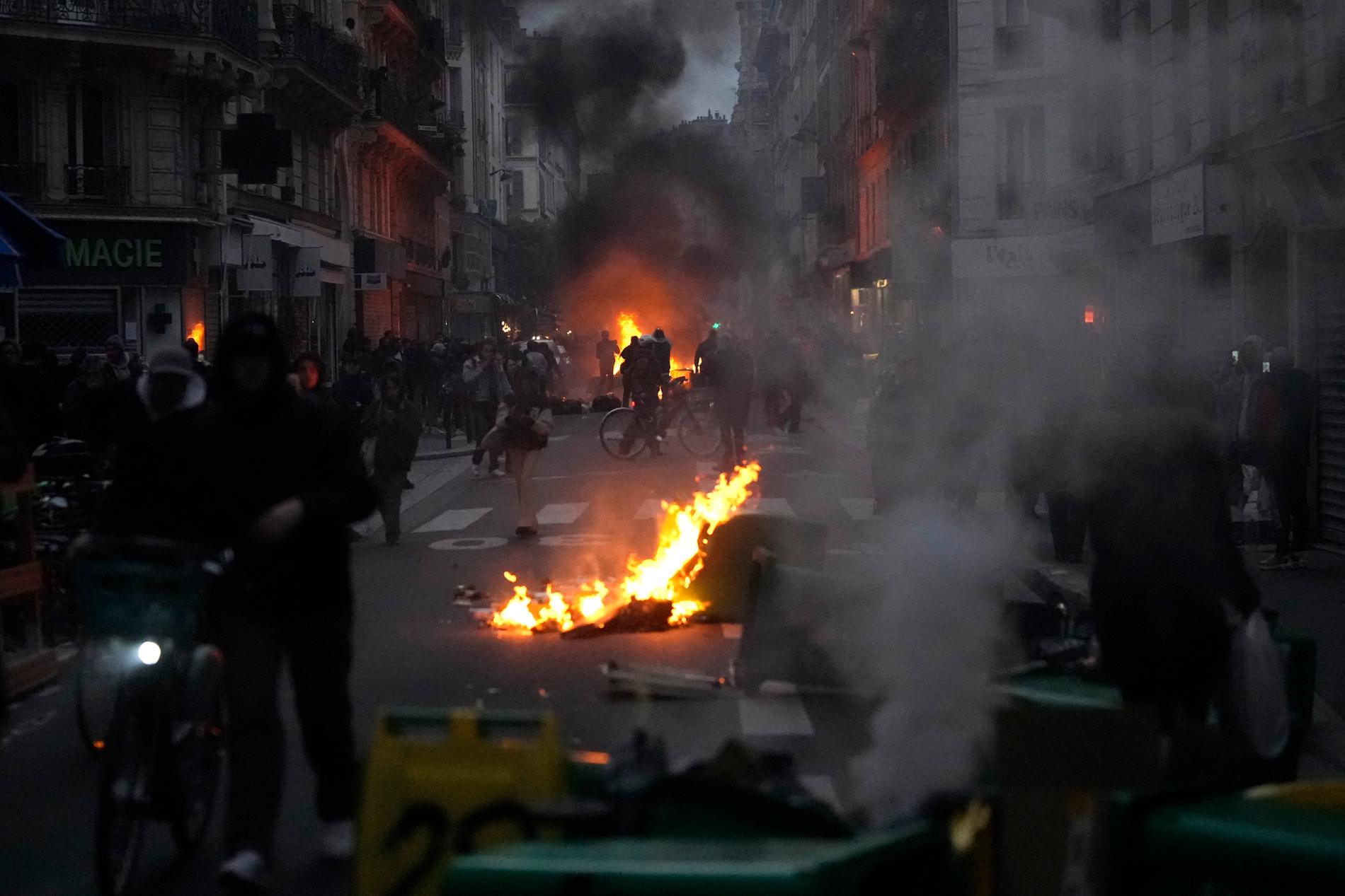 Brinnande soptunnor och demonstranter på Paris gator efter president Macron tal till nationen på måndagskvällen. 
