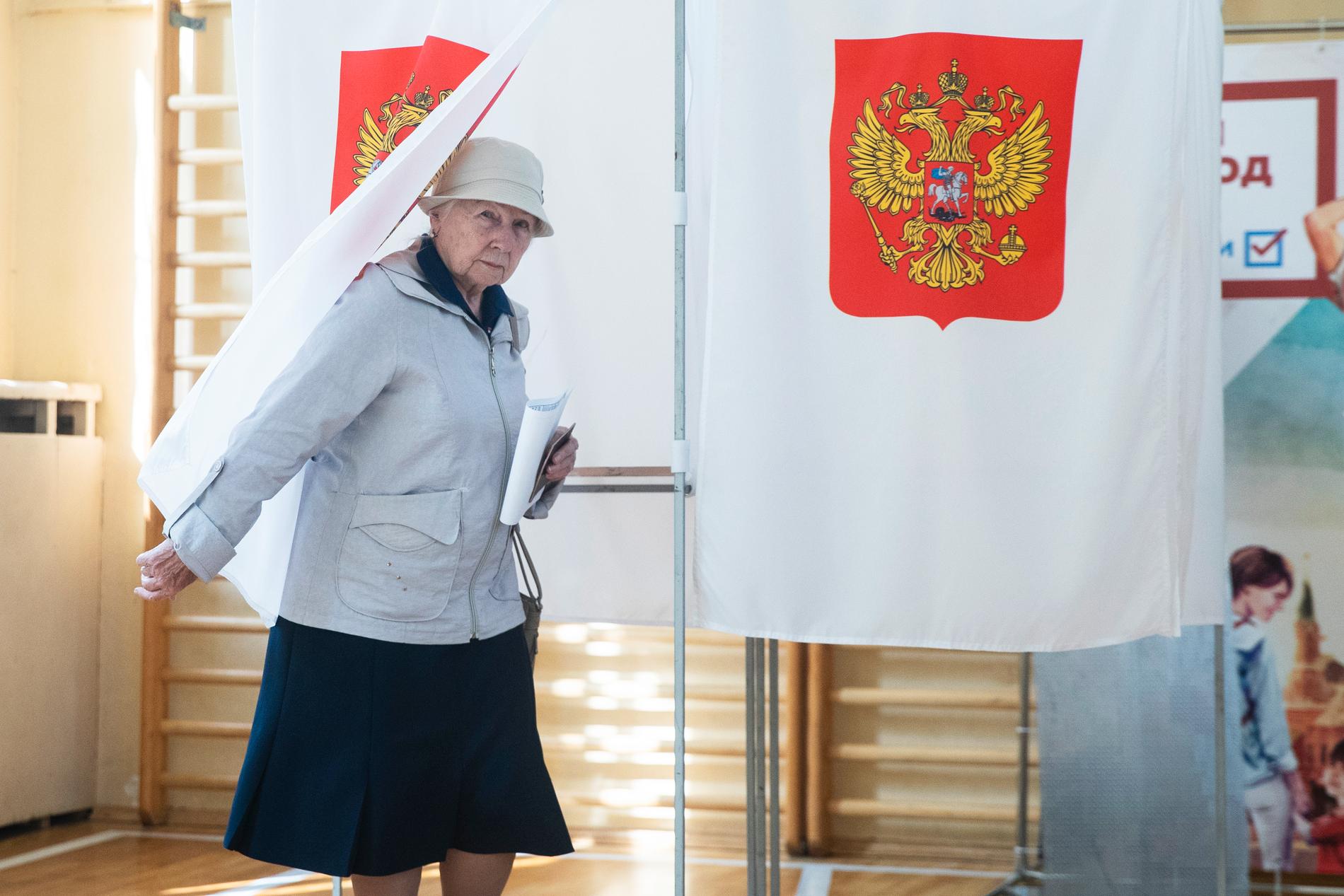 En kvinna lämnar röstbåset i en vallokal i Moskva vid söndagens val.