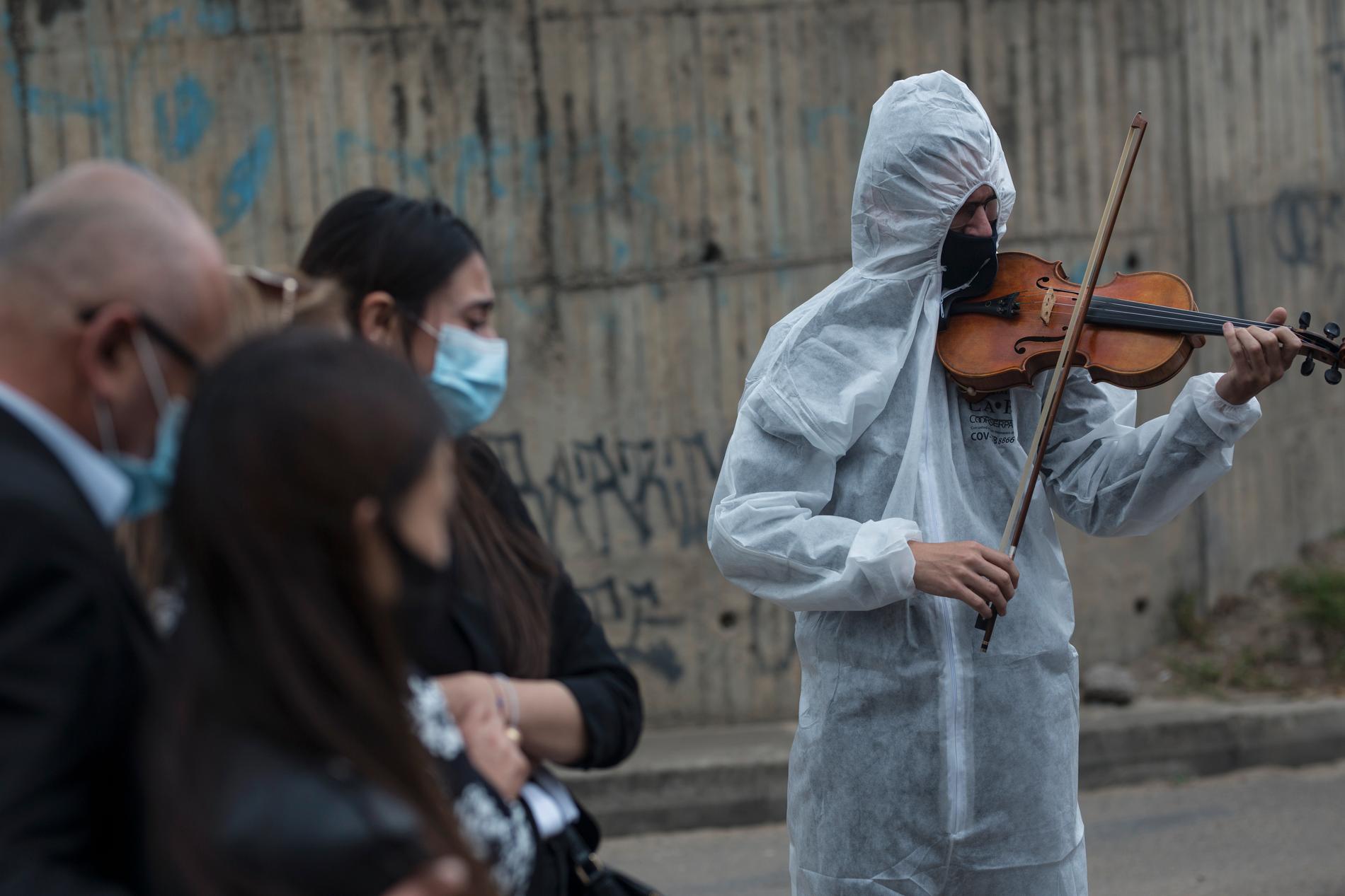 Violinist i full skyddsdräkt på en begravning i Colombia.