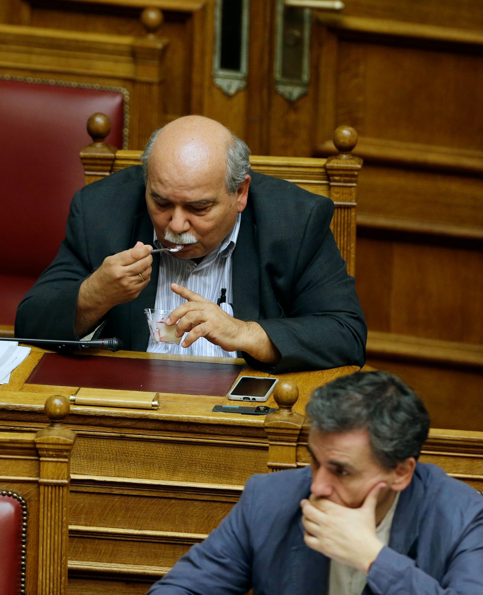 Ministern Nikos Voutsis äter pannacotta under mötet