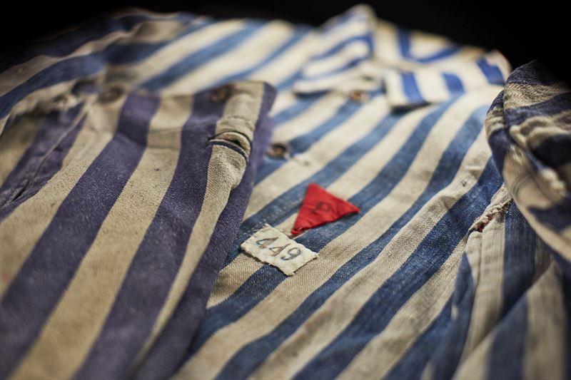 Fångdräkten har tillhört Jan Gondek, före detta fånge  i Auschwitz-Birkenau. Fångarna var tvungna att bära märken som skulle visa deras identitet och grupptillhörighet. P i en röd triangel betydde ”polack”.