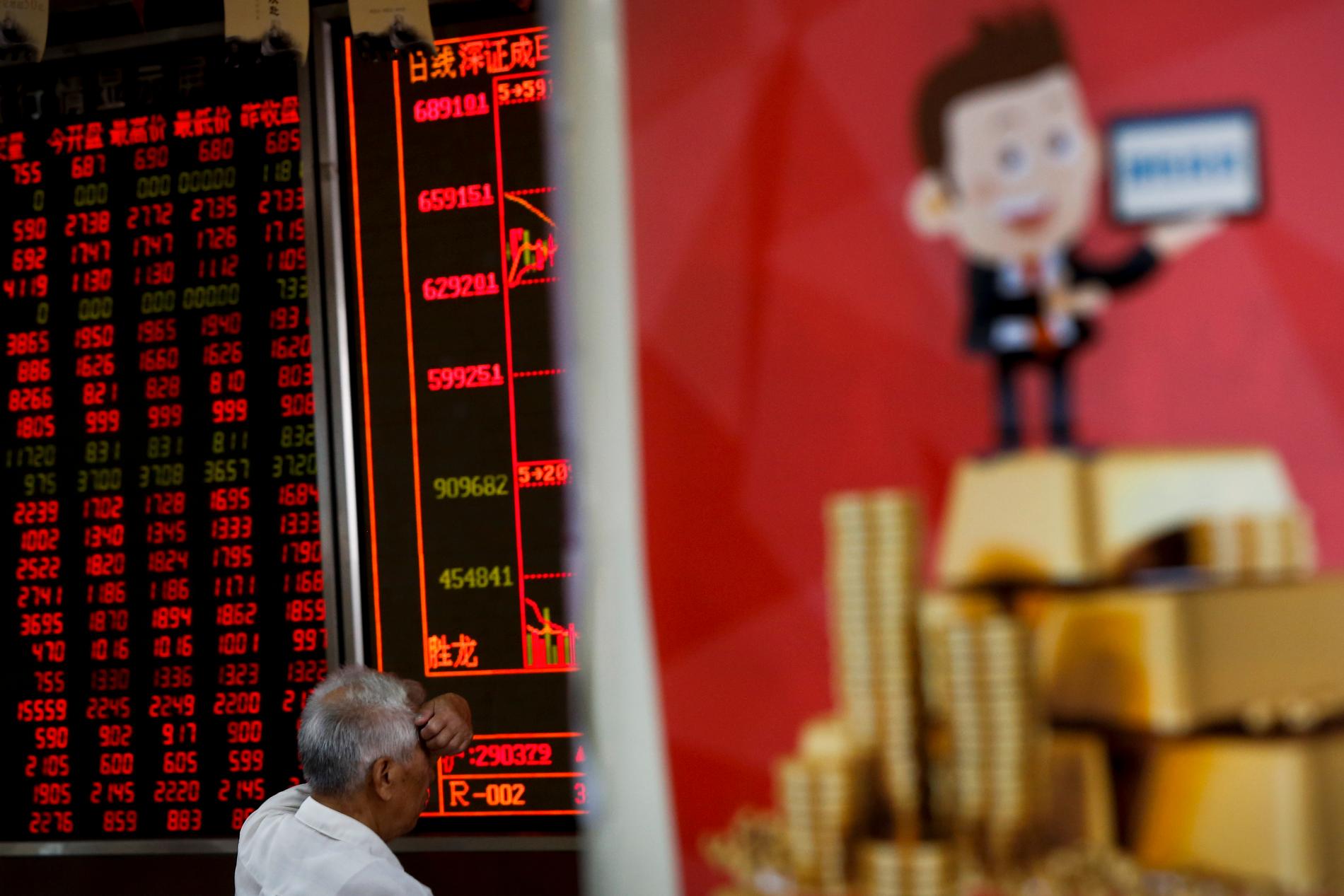 En man kollar på en skärm i Peking, där börsen gick ner under måndagen.