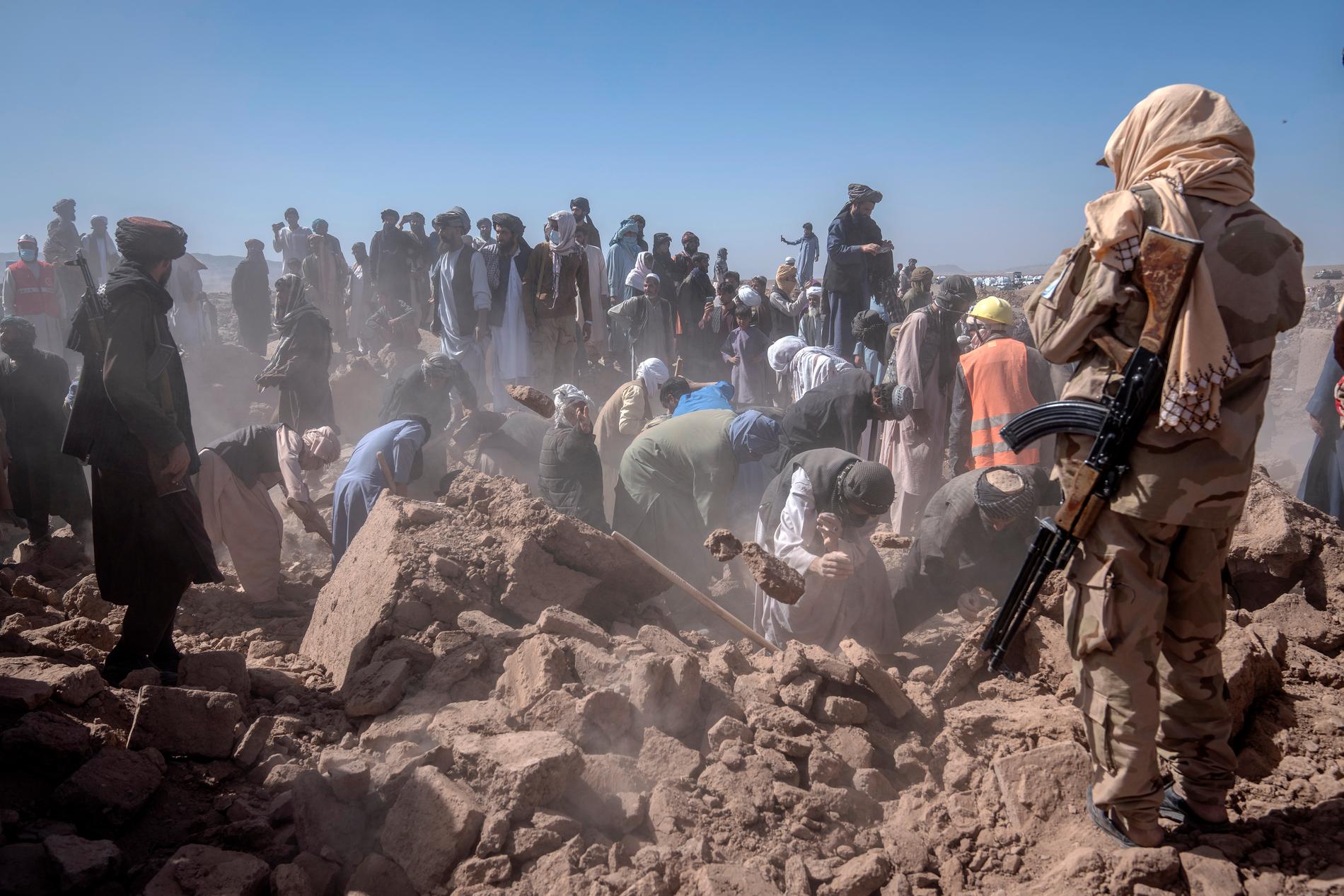Afghanska män gräver efter överlevande med sina bara händer.