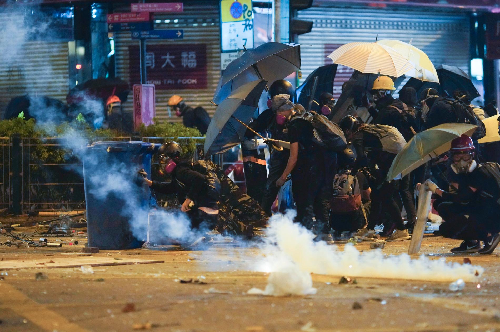 Aktivister i Hongkong söker skydd under sina paraplyer mot polisens tårgas vid en protest i mitten av november.
