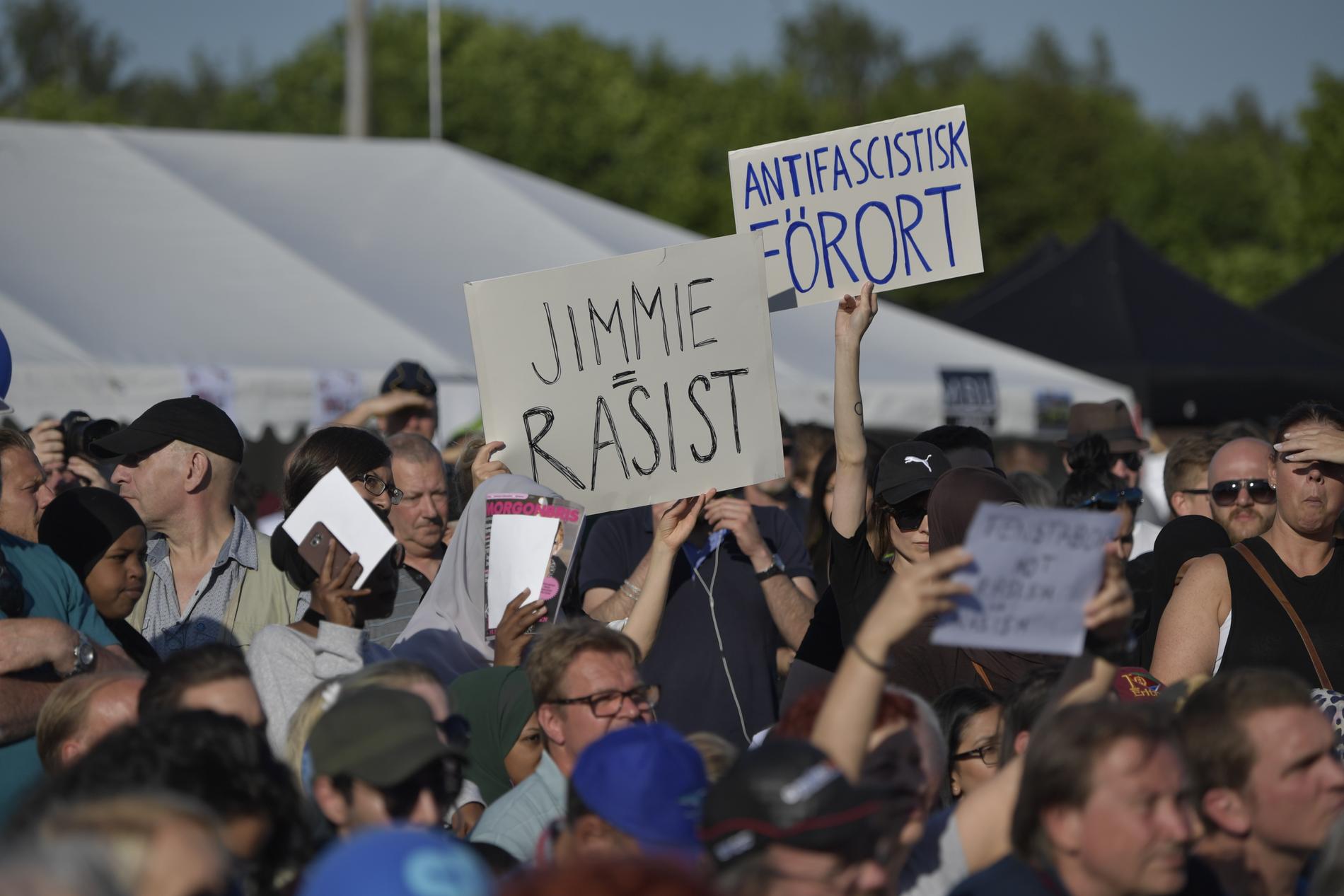 Folk i publiken höll upp plakat med ordet rasist. 