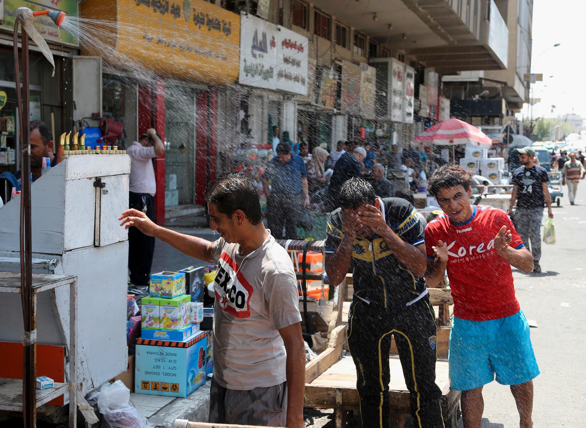 Heta somrar är vanliga i Irak. Här svalkar sig män på en gata i Bagdad i augusti 2016.