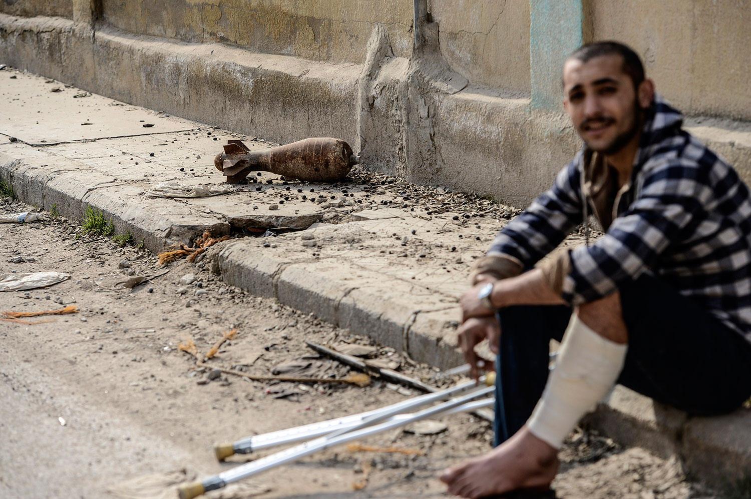 En skadad kurdisk soldat på trottoarkanten. Några meter ifrån en granat.