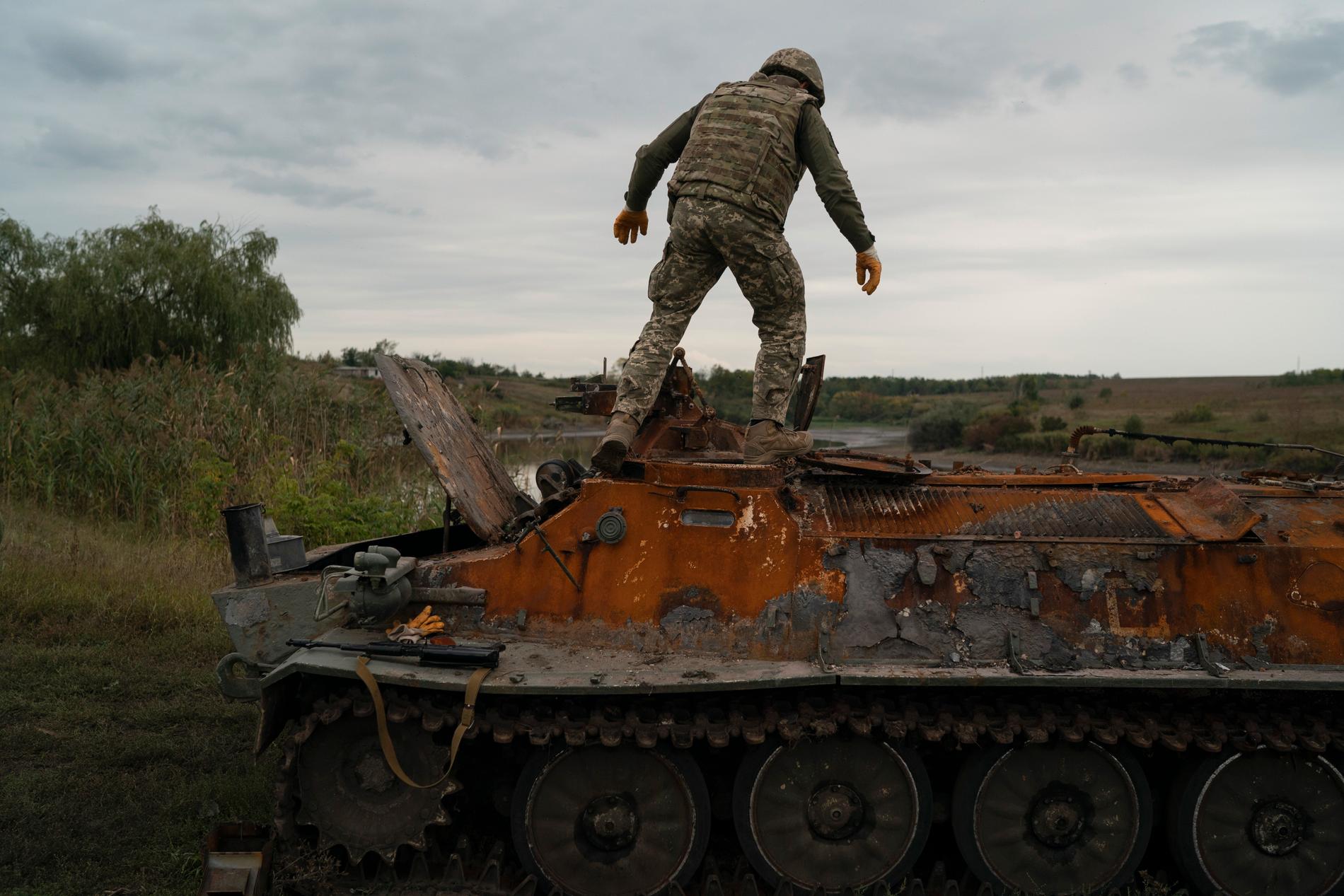 En ukrainsk soldat på ett utbränt ryskt stridsfordon.