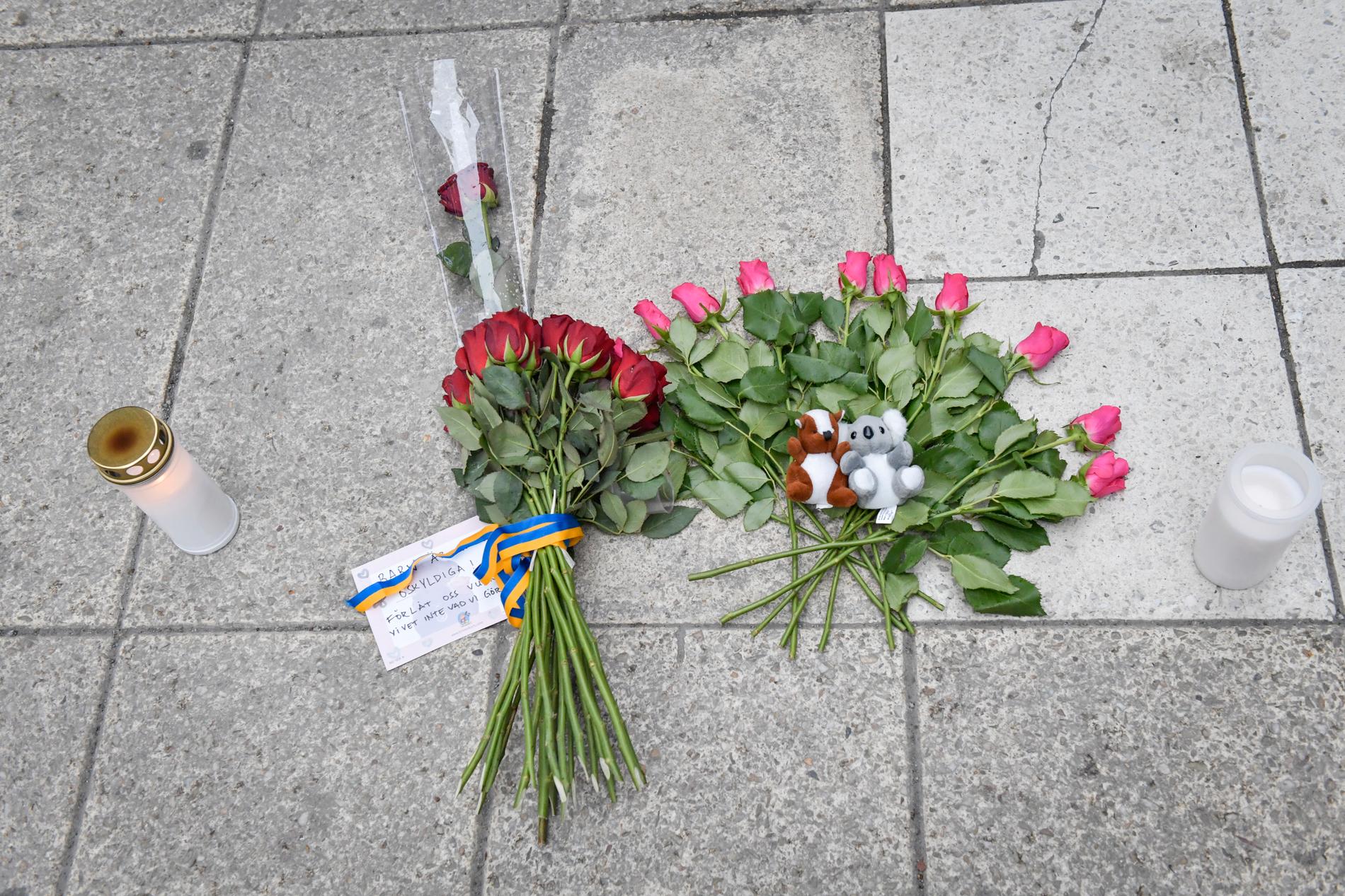 Blommor och ljus på Drottninggatan på lördagsmorgonen efter attacken förra året.