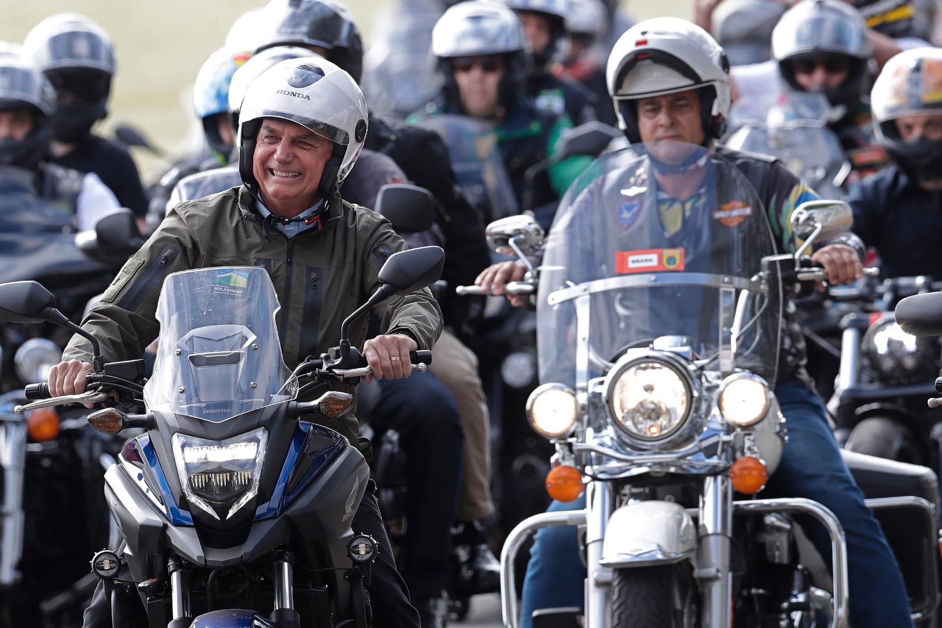 Brasiliens president Jair Bolsonaro, till vänster, leder en motorcykelparad för att hedra Mors dag.