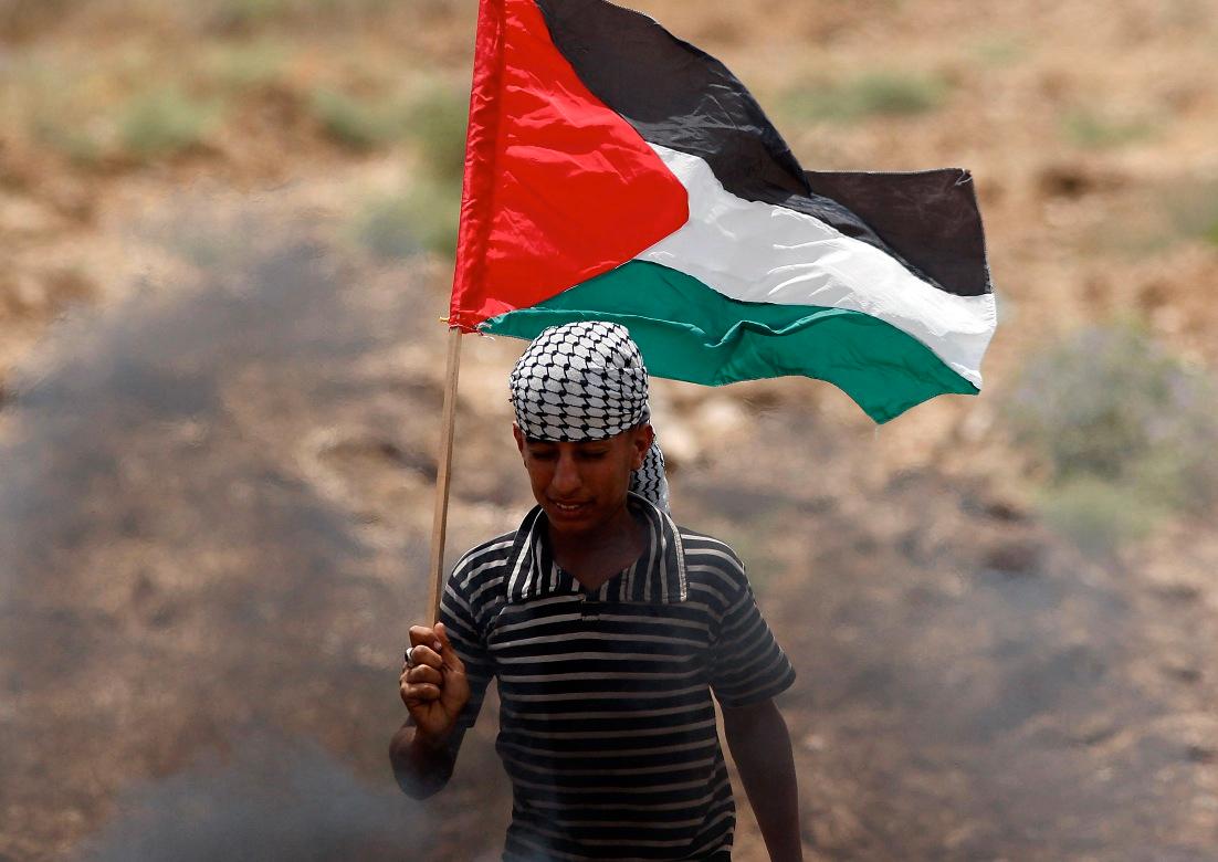 En ung pojke håller den palestinska flaggan under en protestmarsch längs gränsen mot Israel.