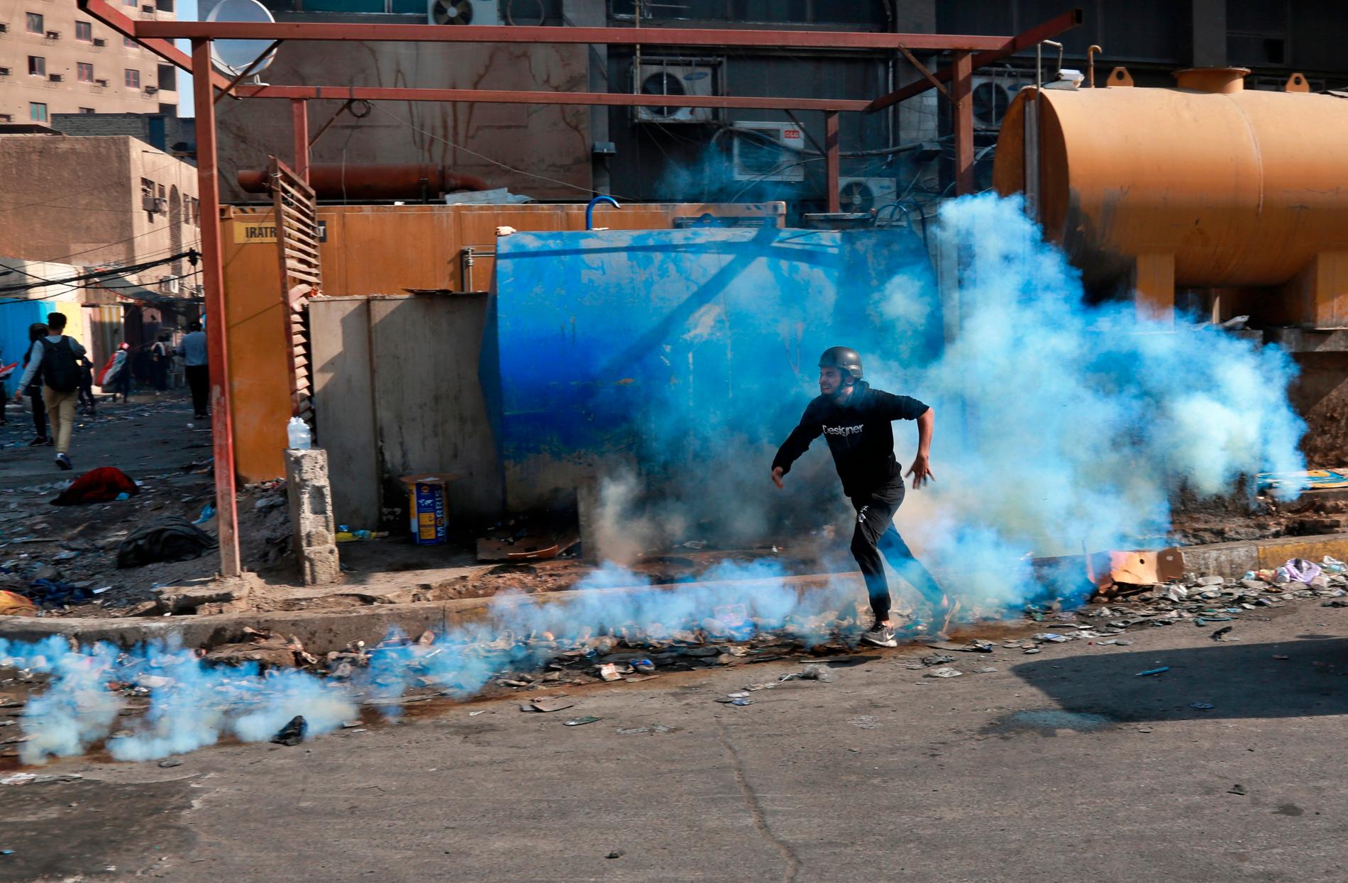En demonstrant försöker undkomma tårgas under protester i Bagdad på onsdagen.