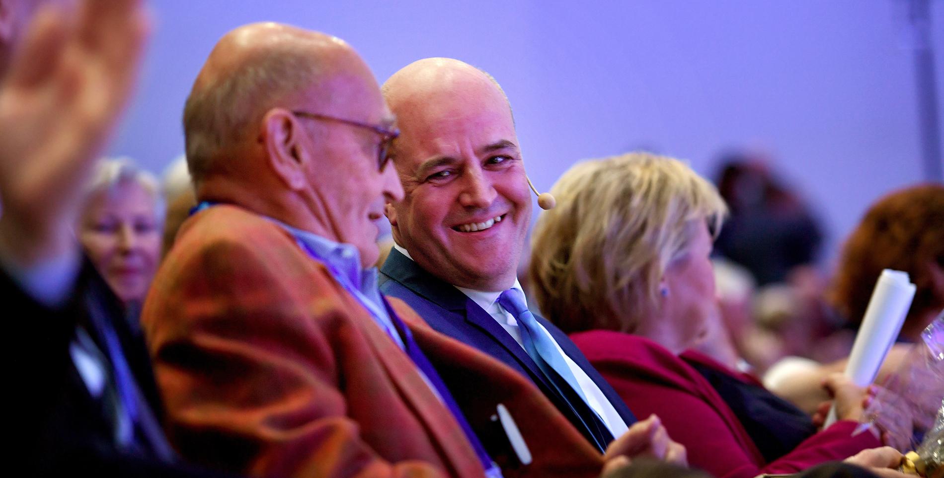 Före detta Moderatledarna Ulf Adelsohn och Fredrik Reinfeldt skrattar tillsammans under Moderaternas partistämma 2019. Inför årets stämma går Adelsohn ut i en intervju och riktar hård kritik mot kollegans, vad han kallar, ”avgörande politiska misstag”.