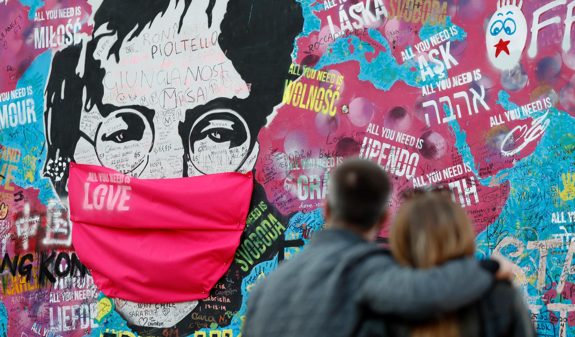 I dag minns många John Lennon, som blev skjuten till döds i New York för 40 år sedan. Här betraktar ett par ”Lennon-väggen” i Prag, där hans porträtt fått ett munskydd under pandemin.