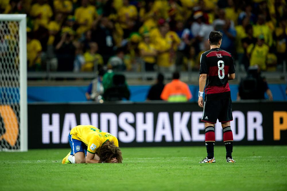 Semifinal mellan Brasilien-Tyskland på Estadio Mineirão i somras. Brasiliens David Luiz Moreira Marinho på knä med huvudet i marken framför Tysklands Mesut Özil.