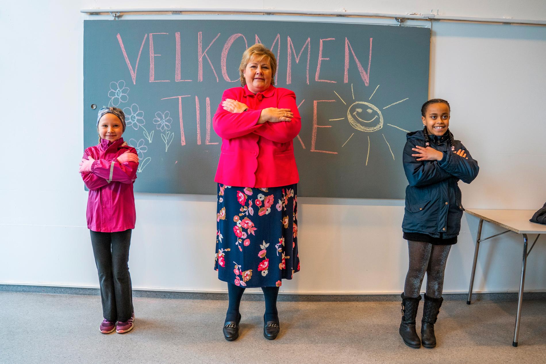 Skolor öppnade i Norge på måndagen, här demonstrerar primiärminister Erna Solberg och elever hälsningsteknik på Ellingsrudasen skolan i Oslo.